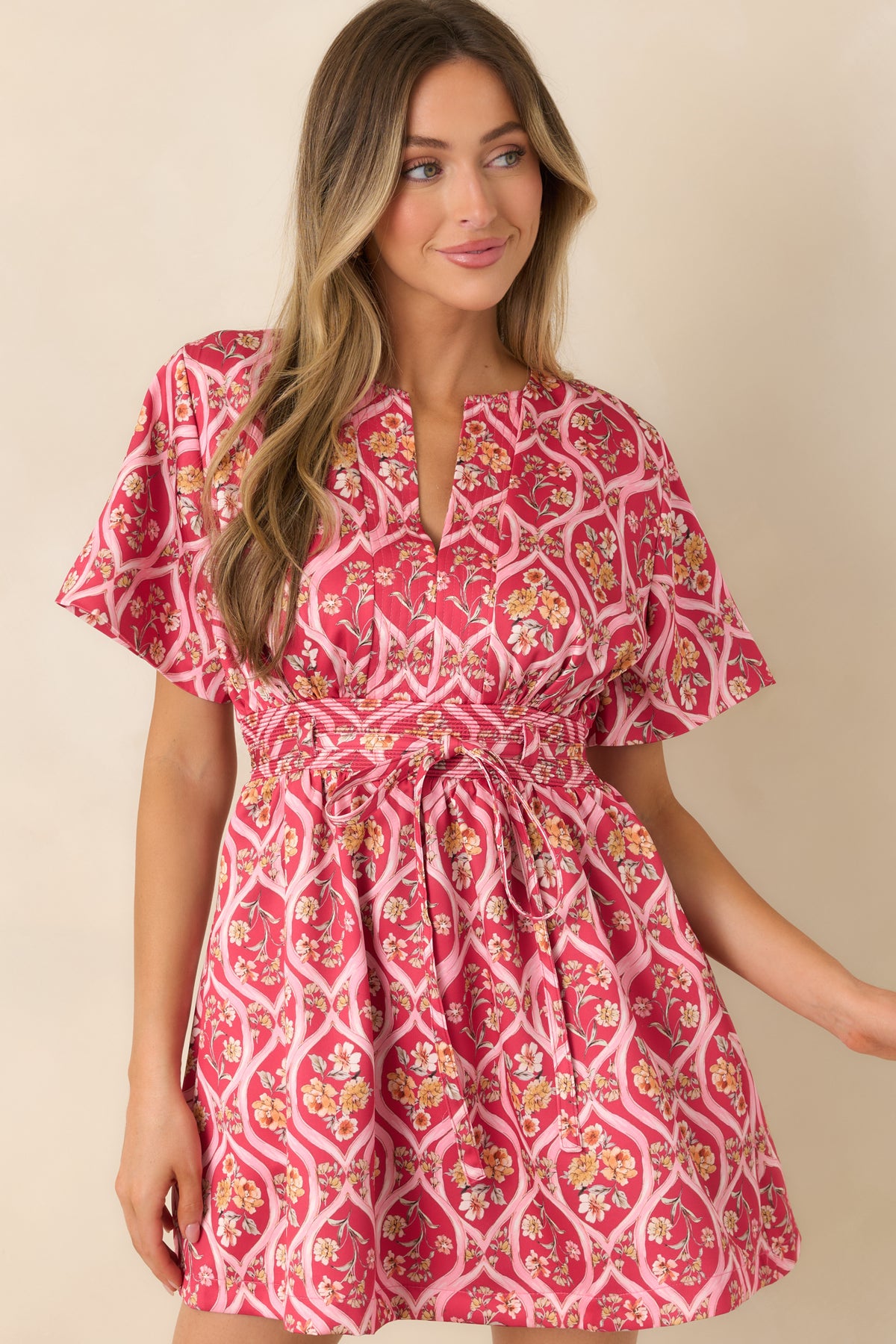 Pink floral mini dress showcasing the wide stitched waistband and decorative front tie.