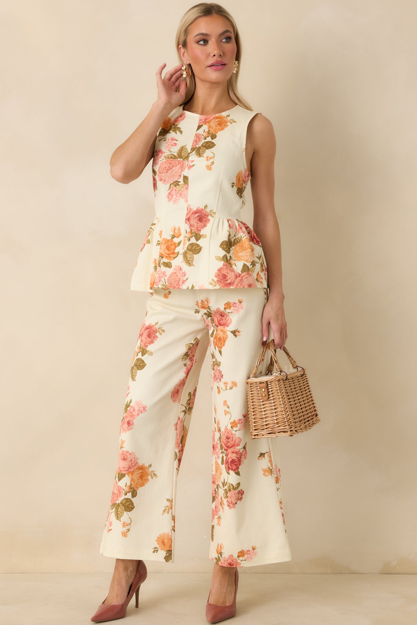 Pink floral print cotton pants with a high-rise waist, wide-leg silhouette, and front button-and-zip closure. Includes belt loops and functional front and back pockets.