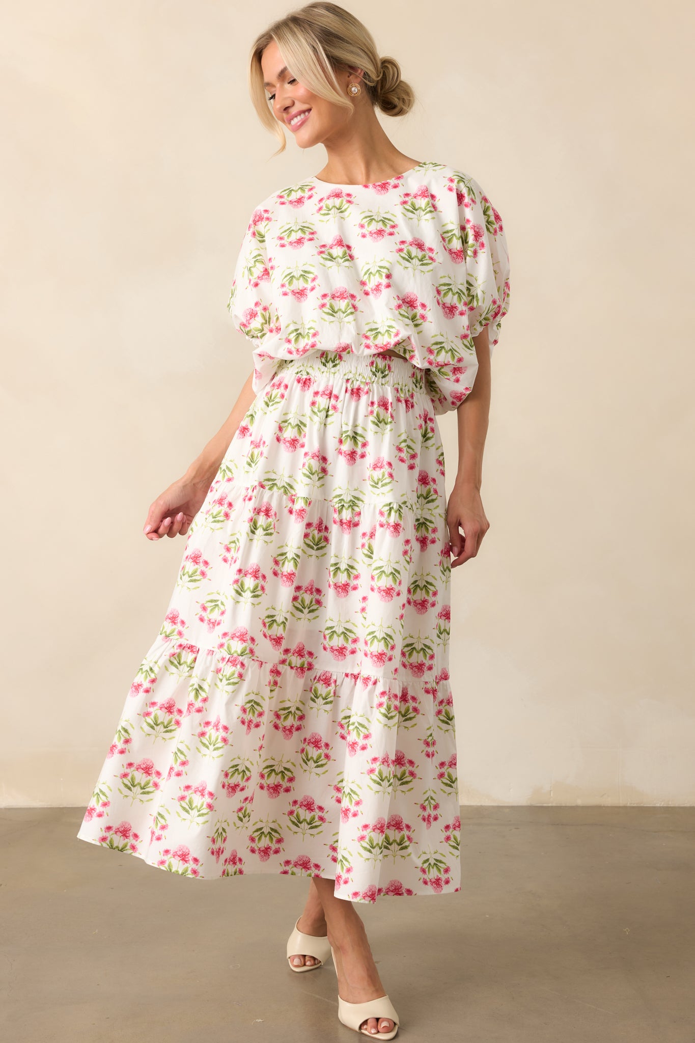 Pink floral print maxi skirt with a white background and tiered panel design, shown in full view to highlight its flowy silhouette.