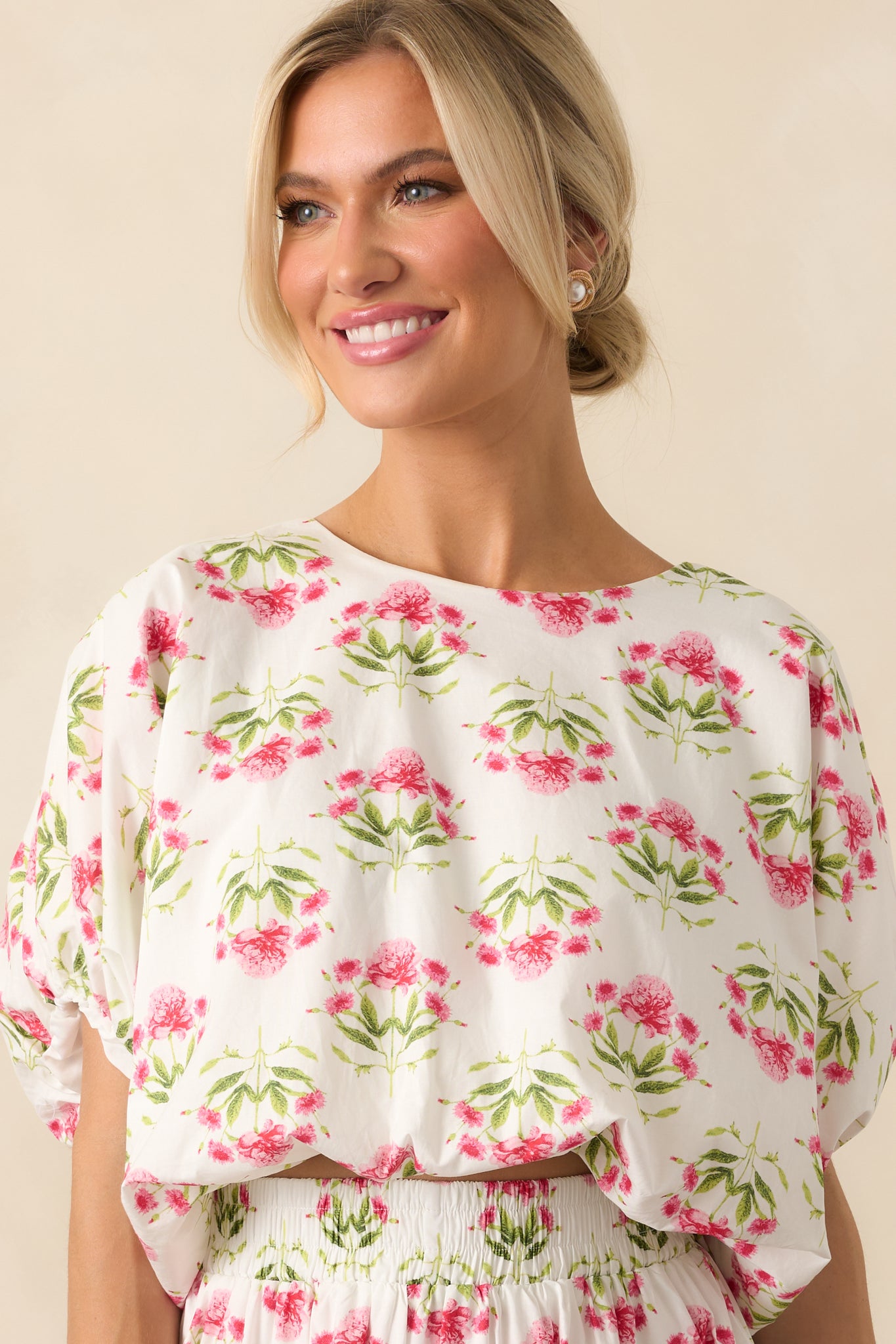 Pink floral print top with a white background and round neckline, shown in a full front view to display the cropped length and relaxed fit