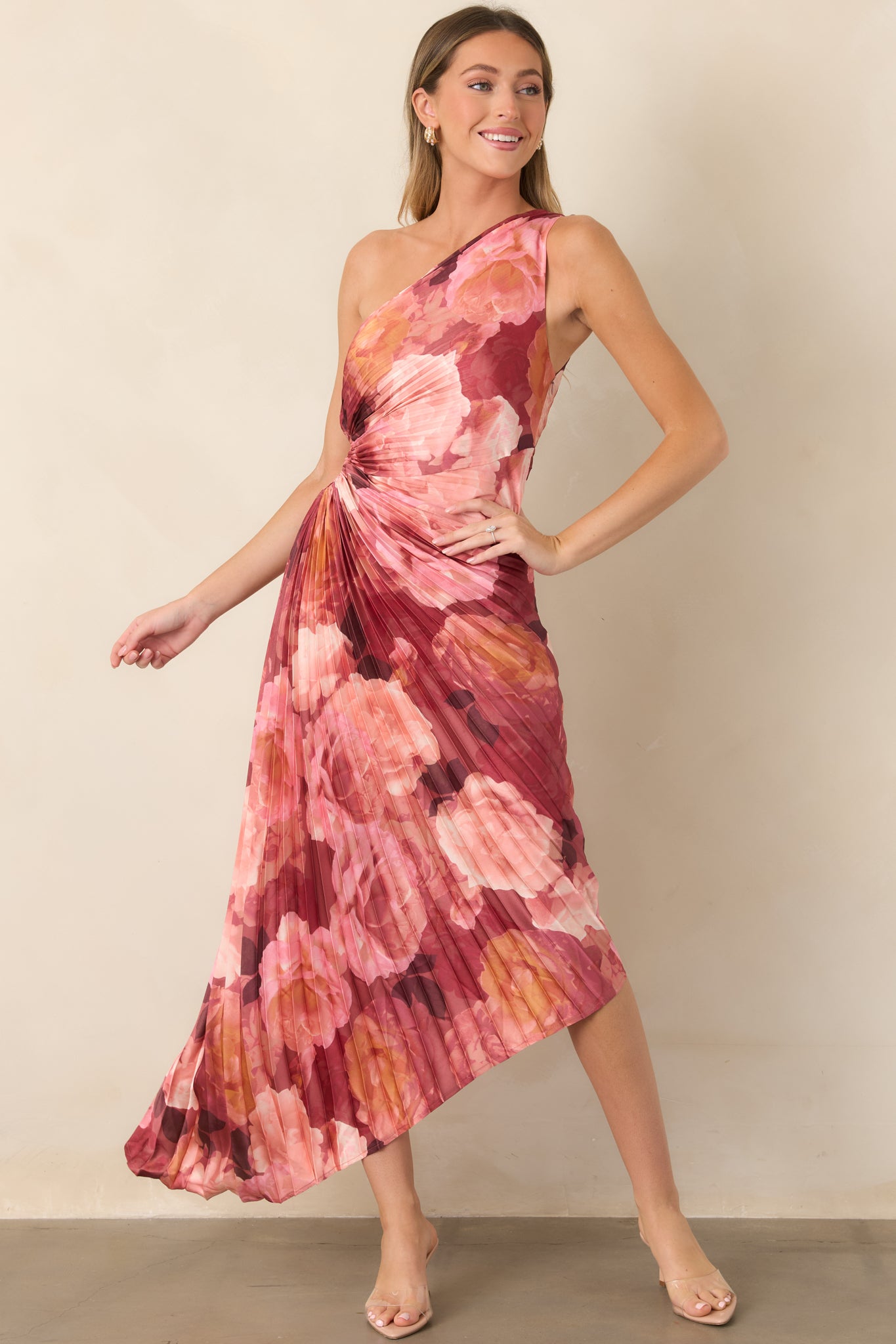 Layered floral satin maxi dress in romantic shades of pink and burgundy, detailed with a side waist cutout, fine pleating, and dramatic asymmetrical skirt.