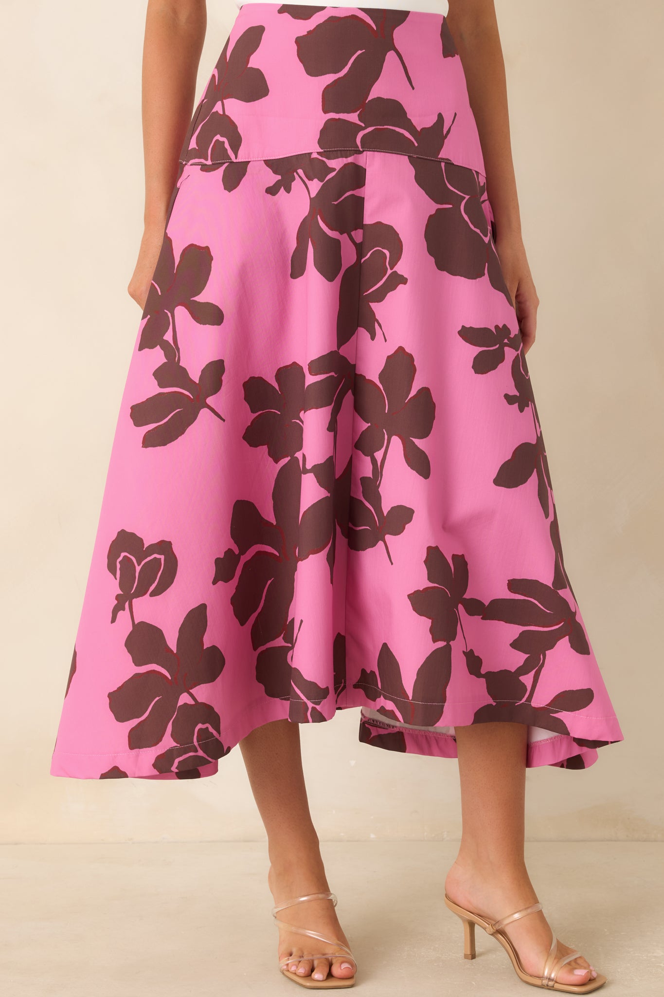 Close view of the pink skirt highlighting the wide fitted waistband, oversized chocolate brown floral print, and smooth cotton fabric.