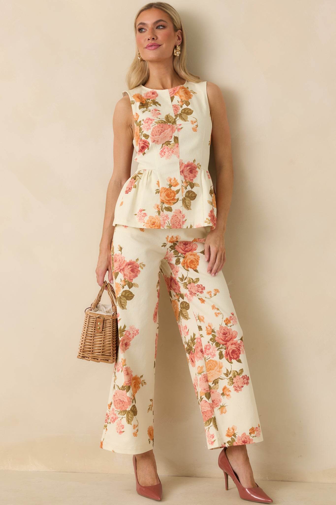 Structured pink floral peplum top showcasing a sleeveless cut, round neckline, and flared peplum hem. Fitted at the waist for a flattering, tailored look.