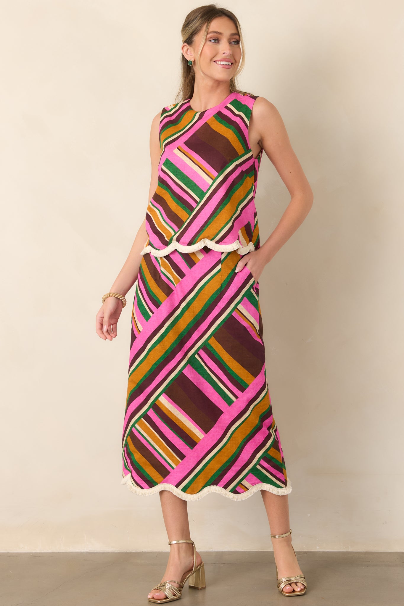 Sleeveless top in a colorful pink geometric stripe print, designed with a relaxed fit and softly scalloped fringe edging.