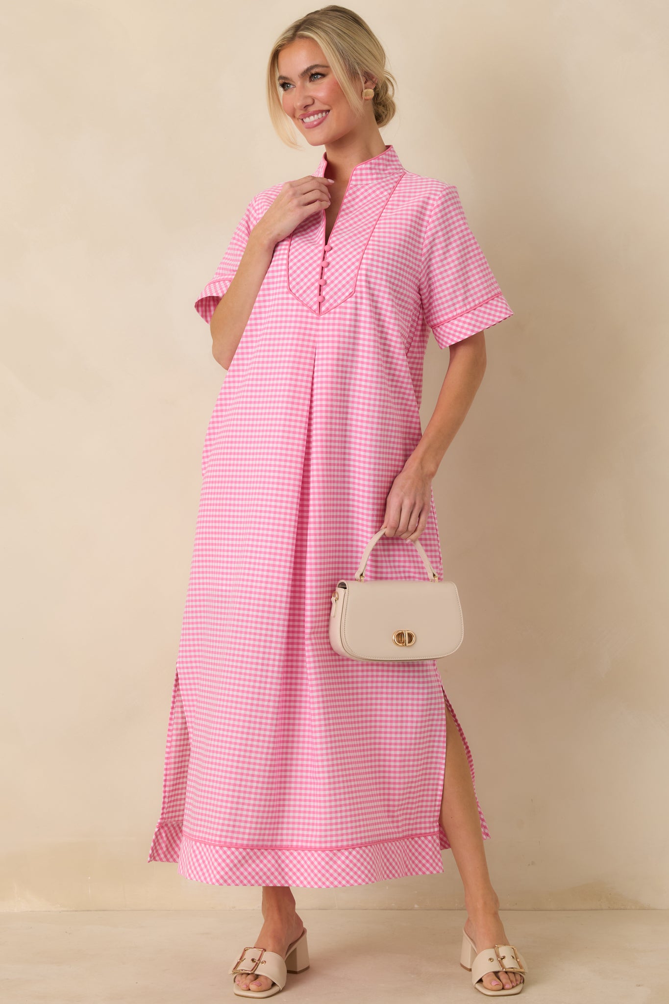Pink gingham maxi dress with a V-neckline, contrast trim, short sleeves, and relaxed maxi-length silhouette.