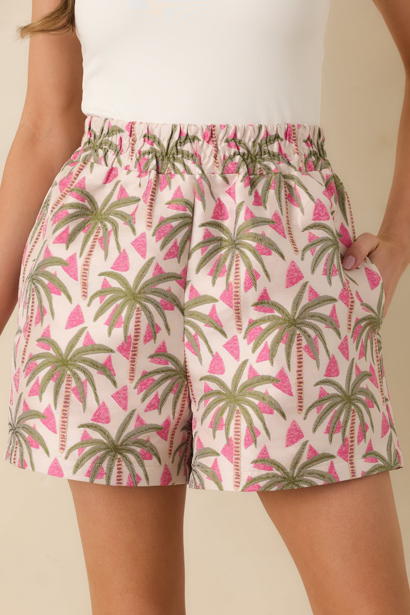 Close-up of the pink jacquard shorts showing the woven texture, palm pattern, and fabric detail.