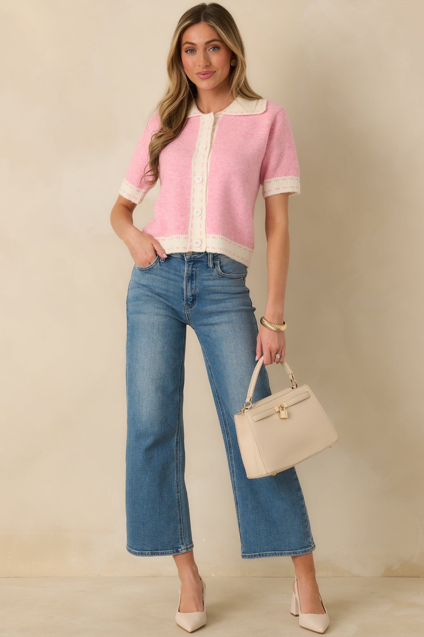 Pink knit cardigan with ivory contrast trim, button-front closure, short sleeves, and a tailored collar finished with a clean hem.