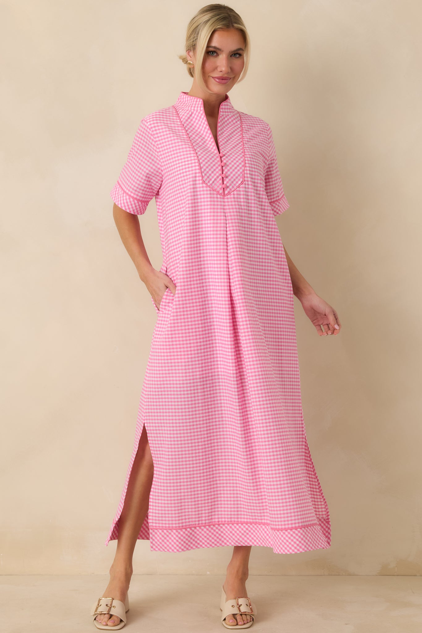 Pink gingham maxi dress shown from the front, highlighting V-neckline, contrast trim, and relaxed shape.