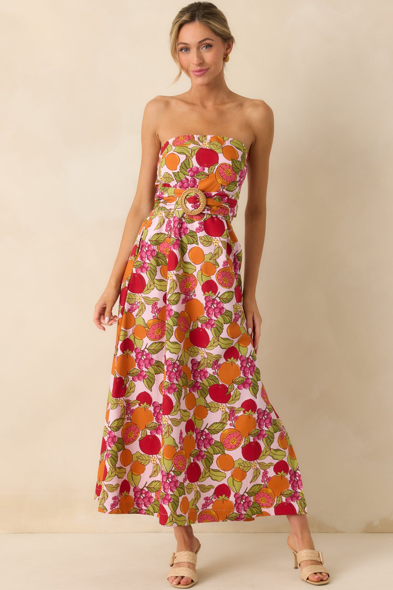 Front view of the pink maxi dress with a multicolor fruit print, featuring a strapless neckline and a flattering basque waist.