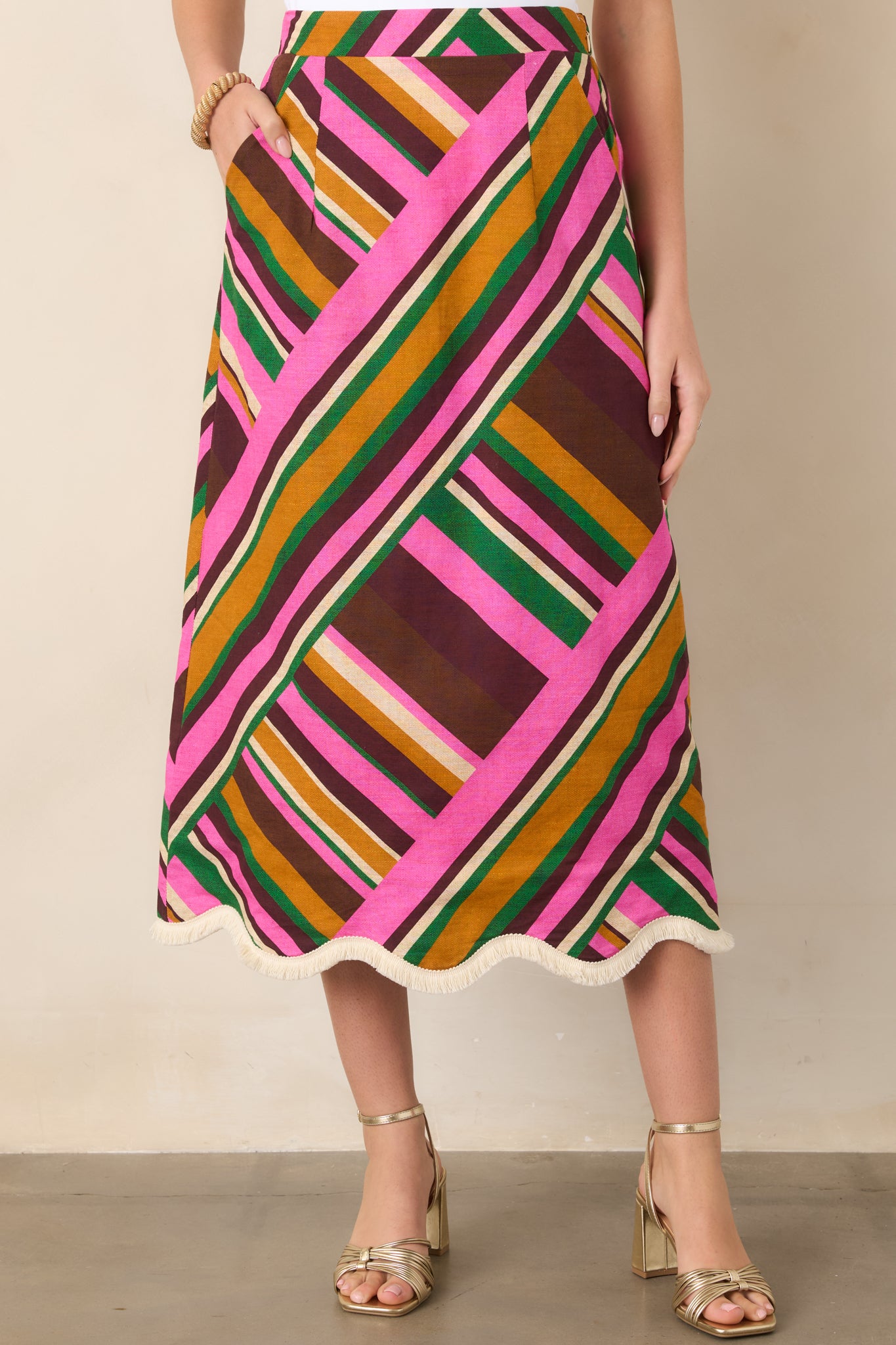 Close view of the pink multi stripe pattern across the softly flared midi skirt, finished with a clean high-rise waistband.