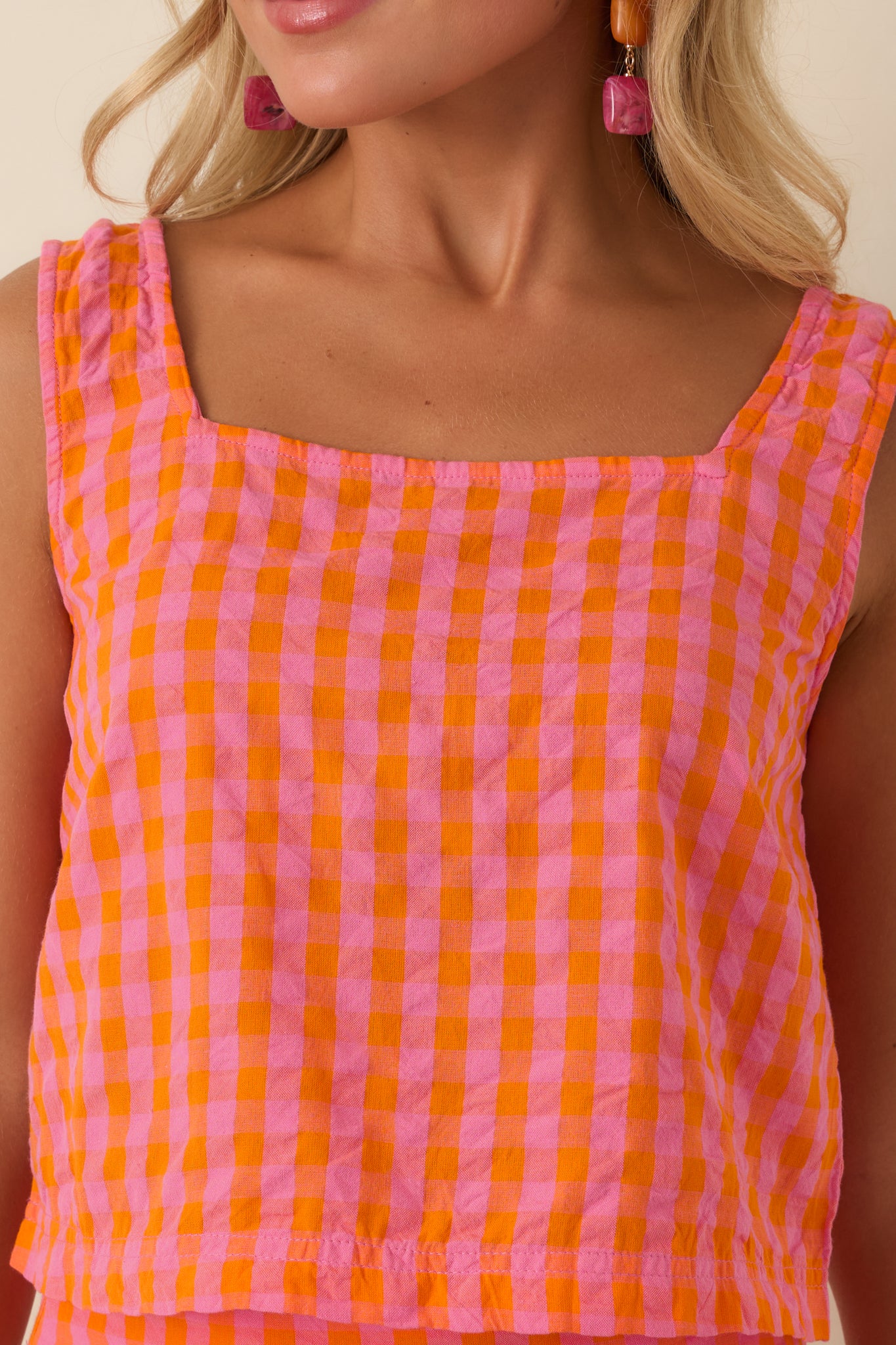 Detailed view of the vibrant pink and orange plaid pattern, square neckline, and lightweight woven cotton fabric.