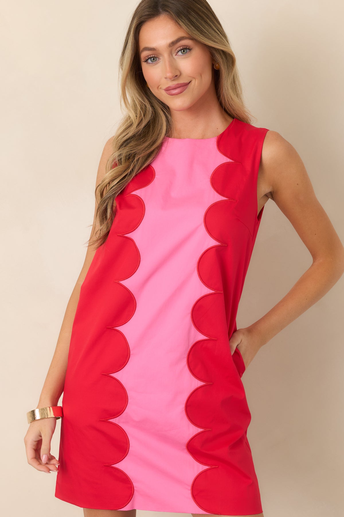 Upper portion of the sleeveless mini dress showcasing the structured pink panel and decorative red scalloped edging.