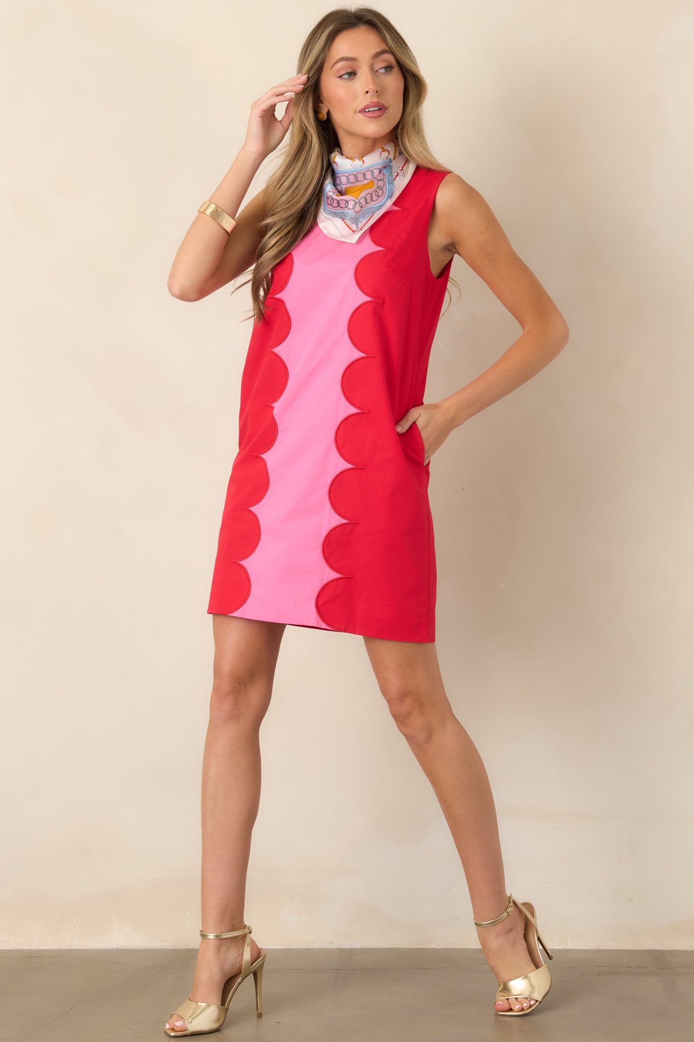 Vibrant pink sleeveless mini dress featuring a structured silhouette framed by striking red scalloped contrast trim and discreet side pockets.
