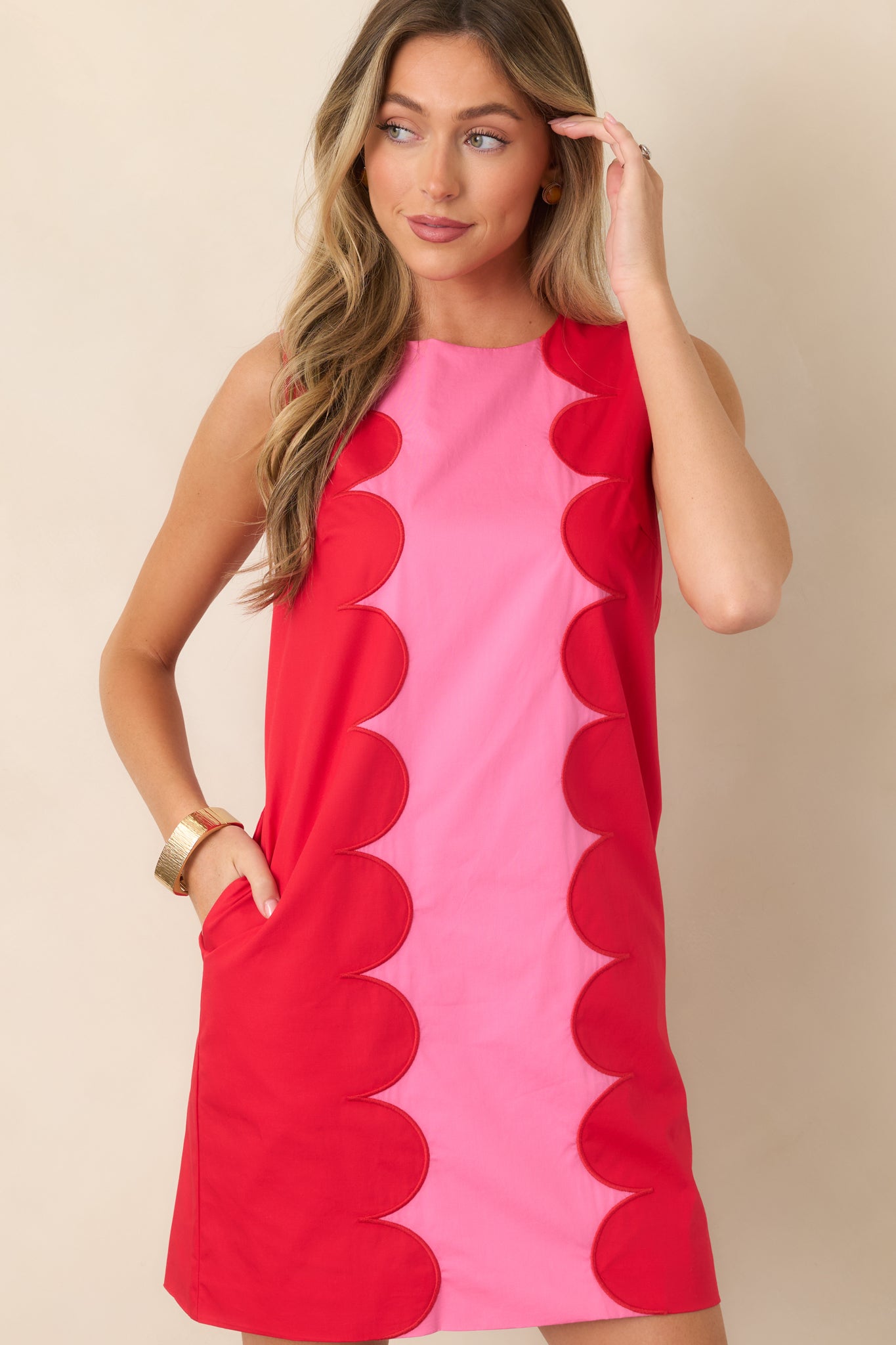 Front detail of the pink mini dress highlighting the vibrant center panel and bold red scalloped contrast trim.