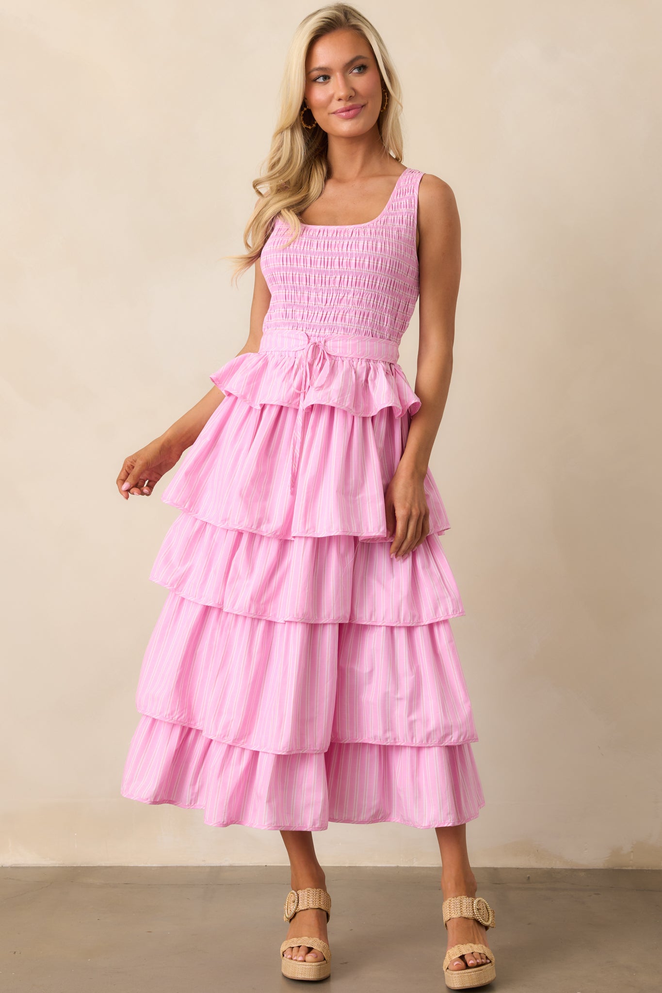 A midi dress with a pink stripe print, fully smocked bodice, and a tiered ruffle skirt for a playful and breezy look.