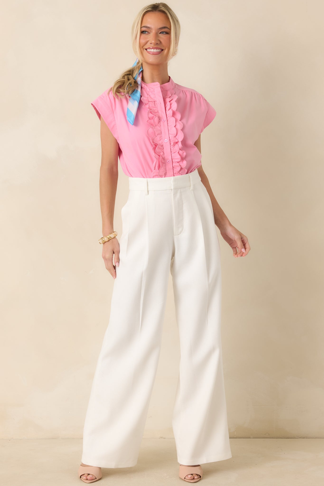 Pink top with a band collar and scalloped ruffle trim running down the front, finished with functional buttons and gently cuffed cap sleeves.
