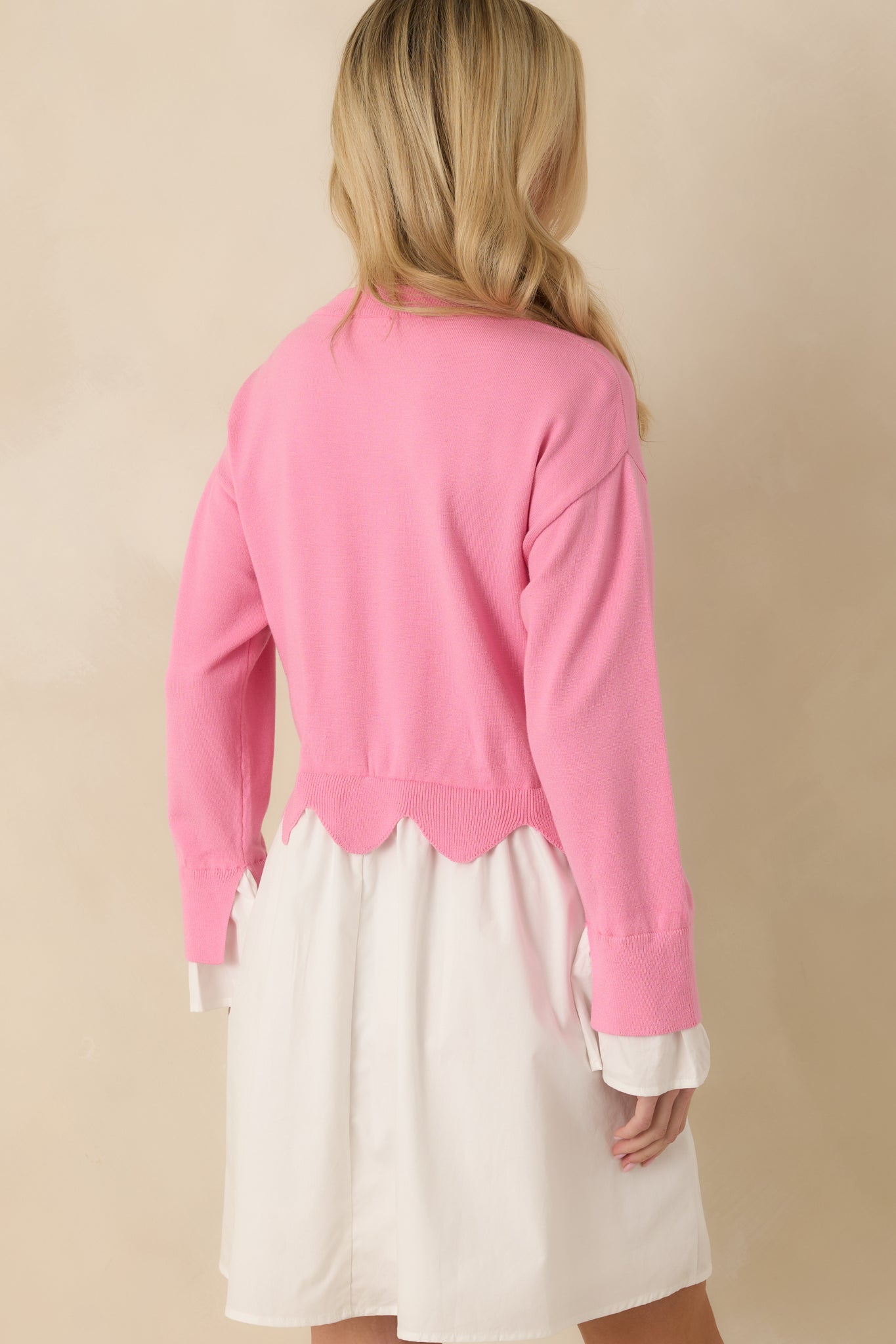 Back view of the pink and white mini dress showing the knit sweater bodice, long sleeves, and relaxed fit with a flowing woven skirt.