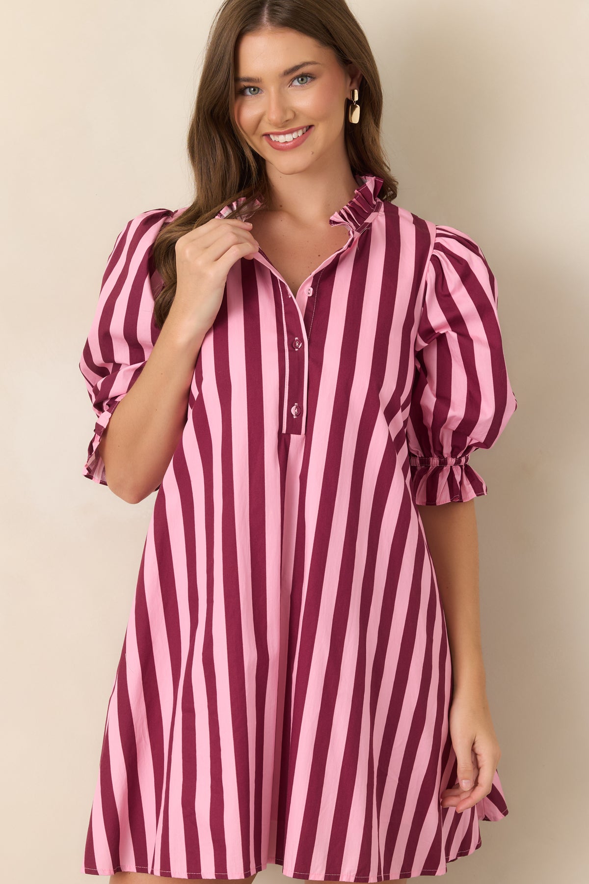 Detailed view of the pink and wine striped dress featuring its voluminous three-quarter sleeve and delicate ruffle cuff.