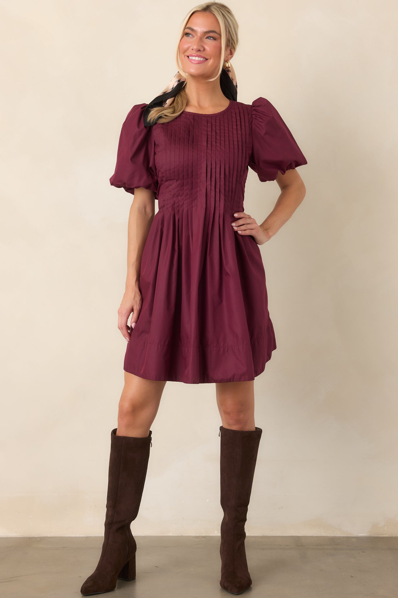 Structured mini dress showcasing rows of delicate pintucking across the bodice, rounded puff sleeves, and a full gathered skirt with side pockets.