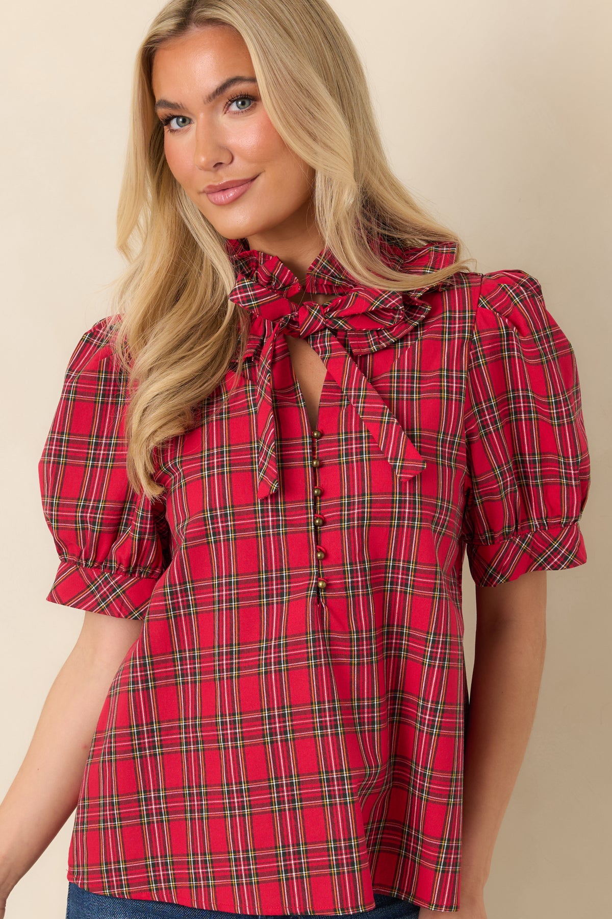 Plaid blouse highlighting the ruffled stand collar and matching fabric bow tied at the neckline.