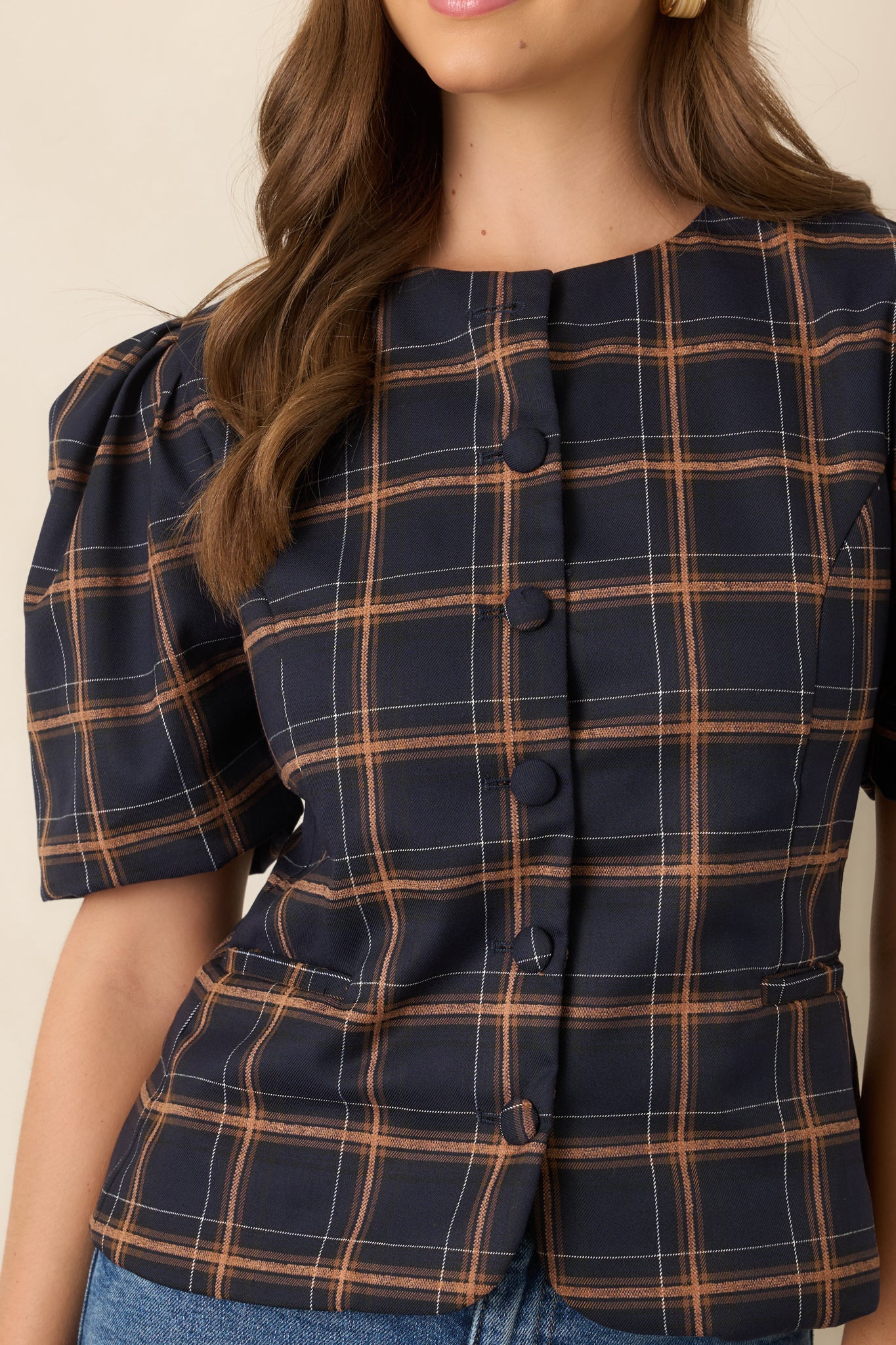 Close-up of the plaid top’s functional fabric-covered buttons and structured woven fabric in navy, camel, and ivory.
