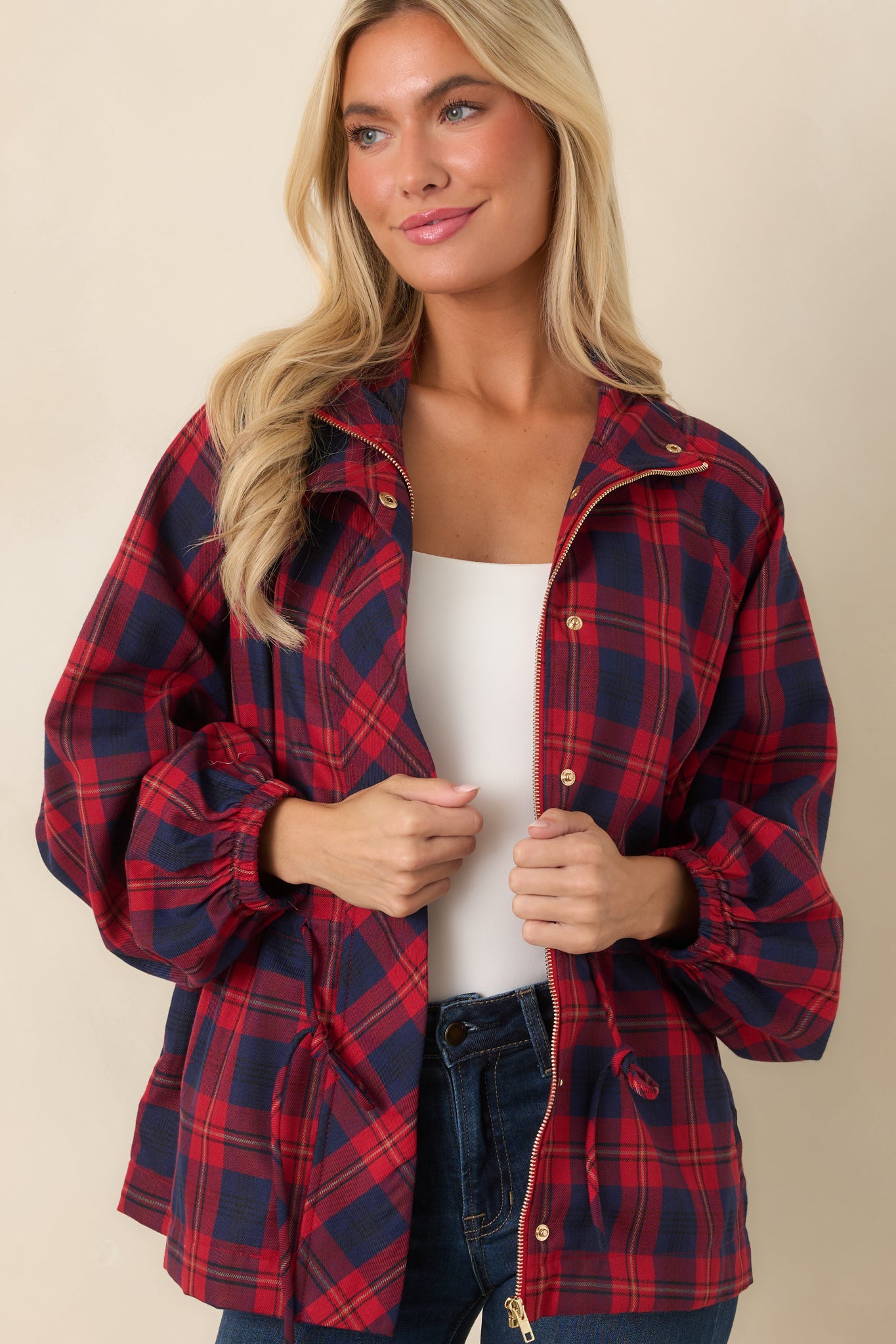 Close view of the jacket highlighting the structured collar, zip-front closure, snap accents, and rich red and navy plaid pattern.