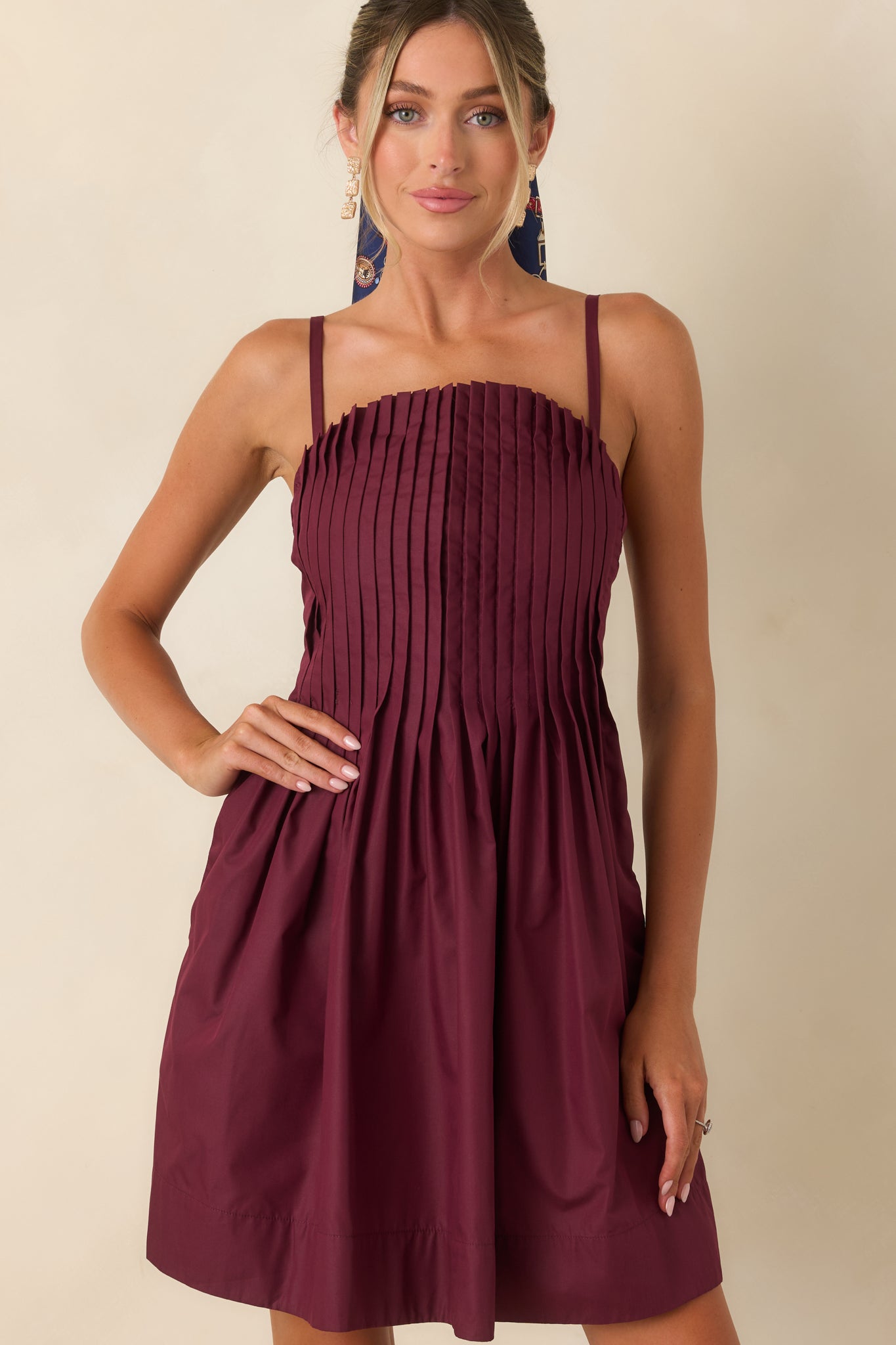 Detailed view of the mini dress highlighting the crisp pleated bodice and adjustable shoulder straps.