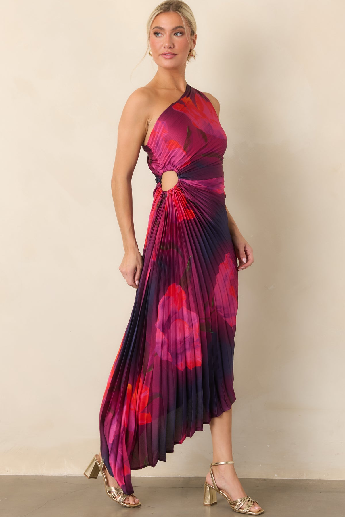 Pleated fabric gives the floral dress a sculpted shape, complemented by a gathered waist and flowing asymmetrical skirt.