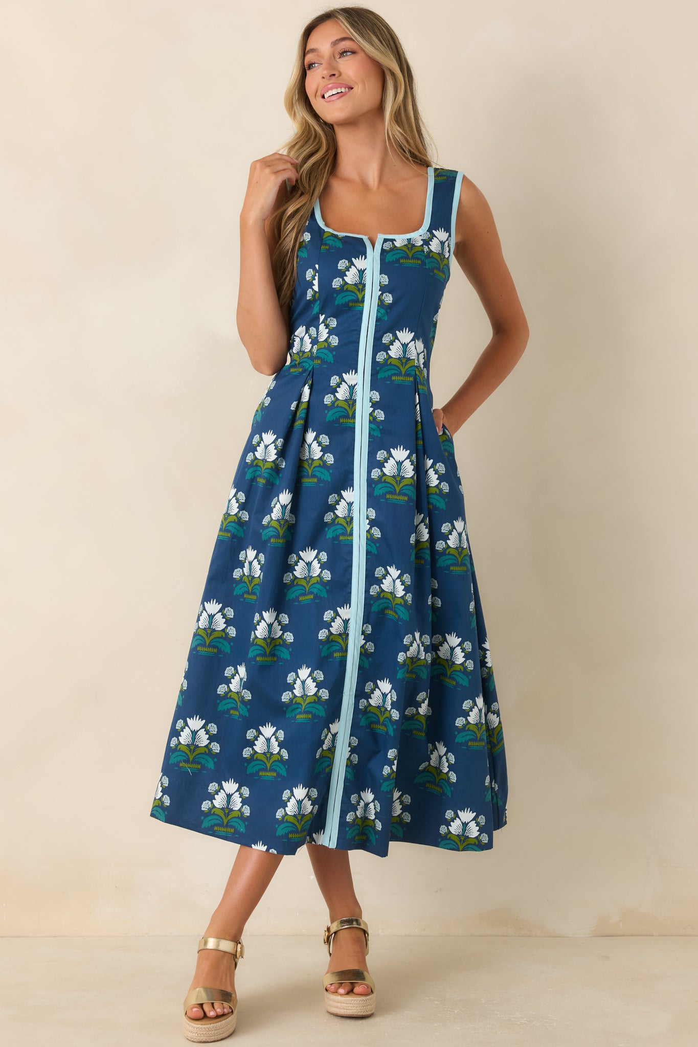 Pleated floral dress with a fitted waist, light blue trim accents, and graceful movement.