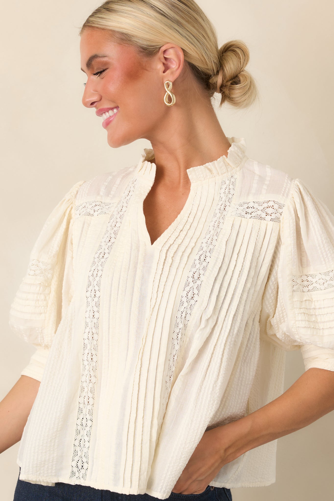 Blouse featuring intricate lace inserts framed by vertical pleats and a softly gathered ruffle neckline.