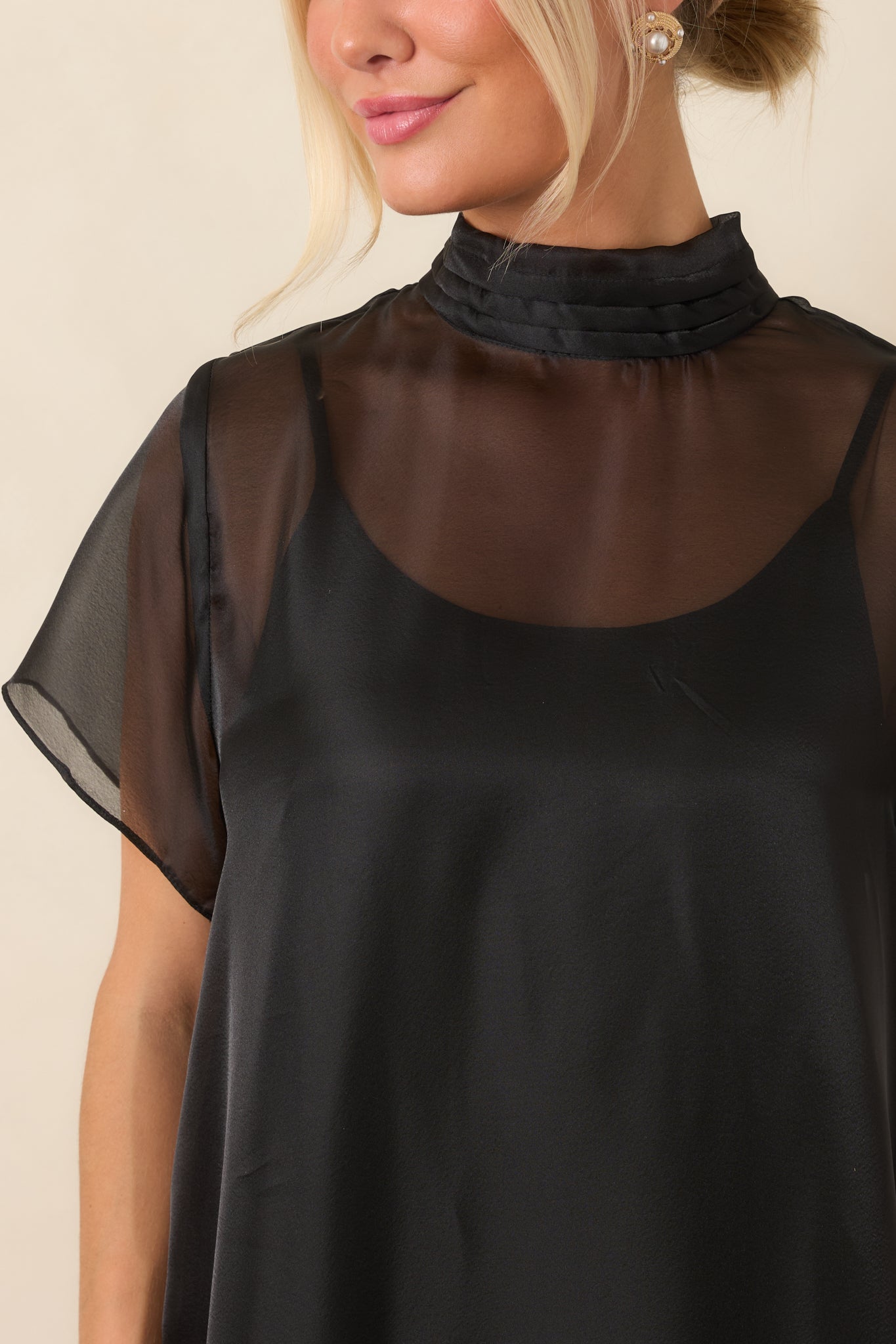 Close-up of the high pleated mock neckline and short sheer sleeve, highlighting the delicate organza texture and refined detailing.