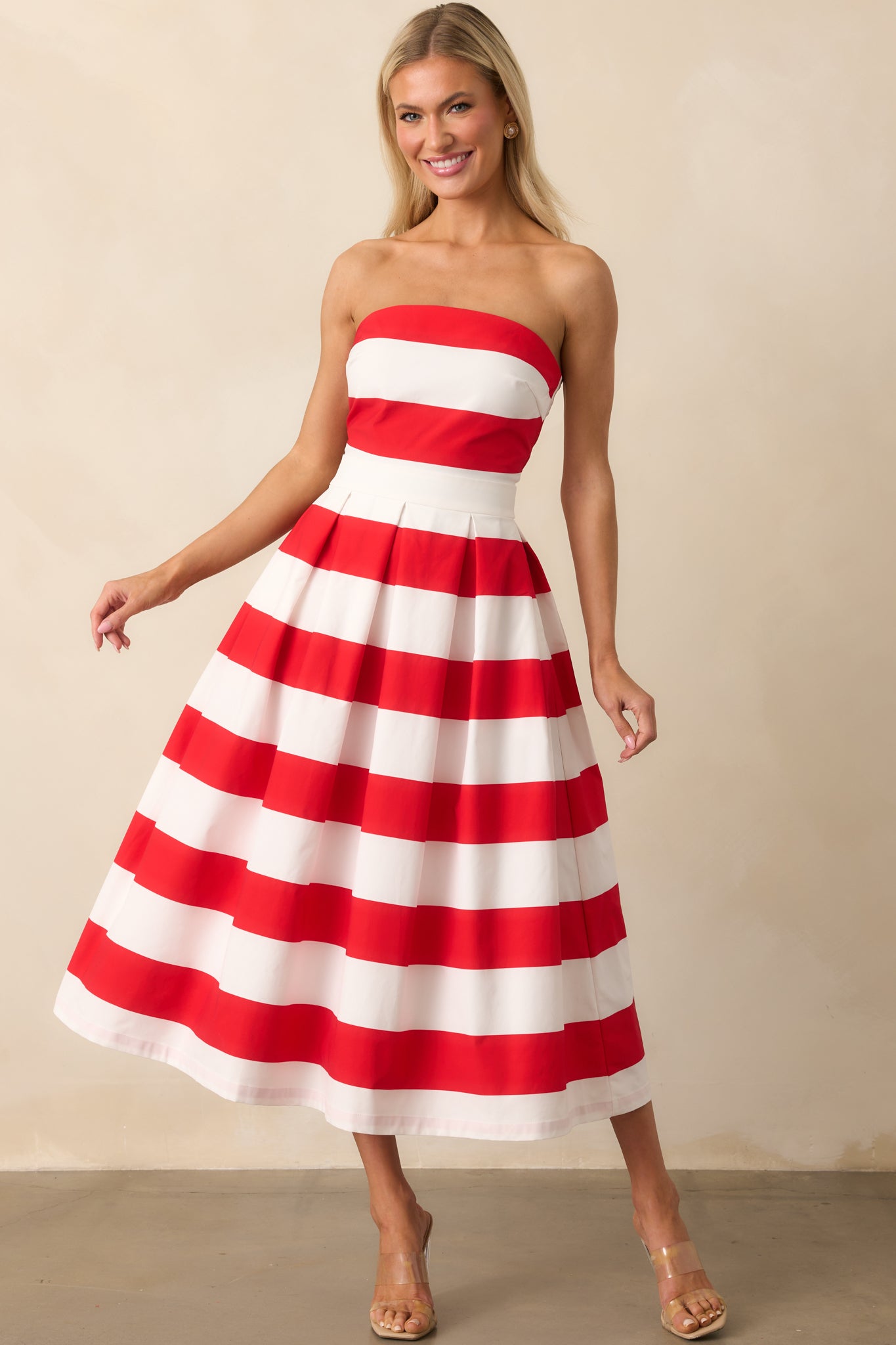 The pleated red and white striped dress shown with a slight side tilt, highlighting the volume and shape of the skirt.