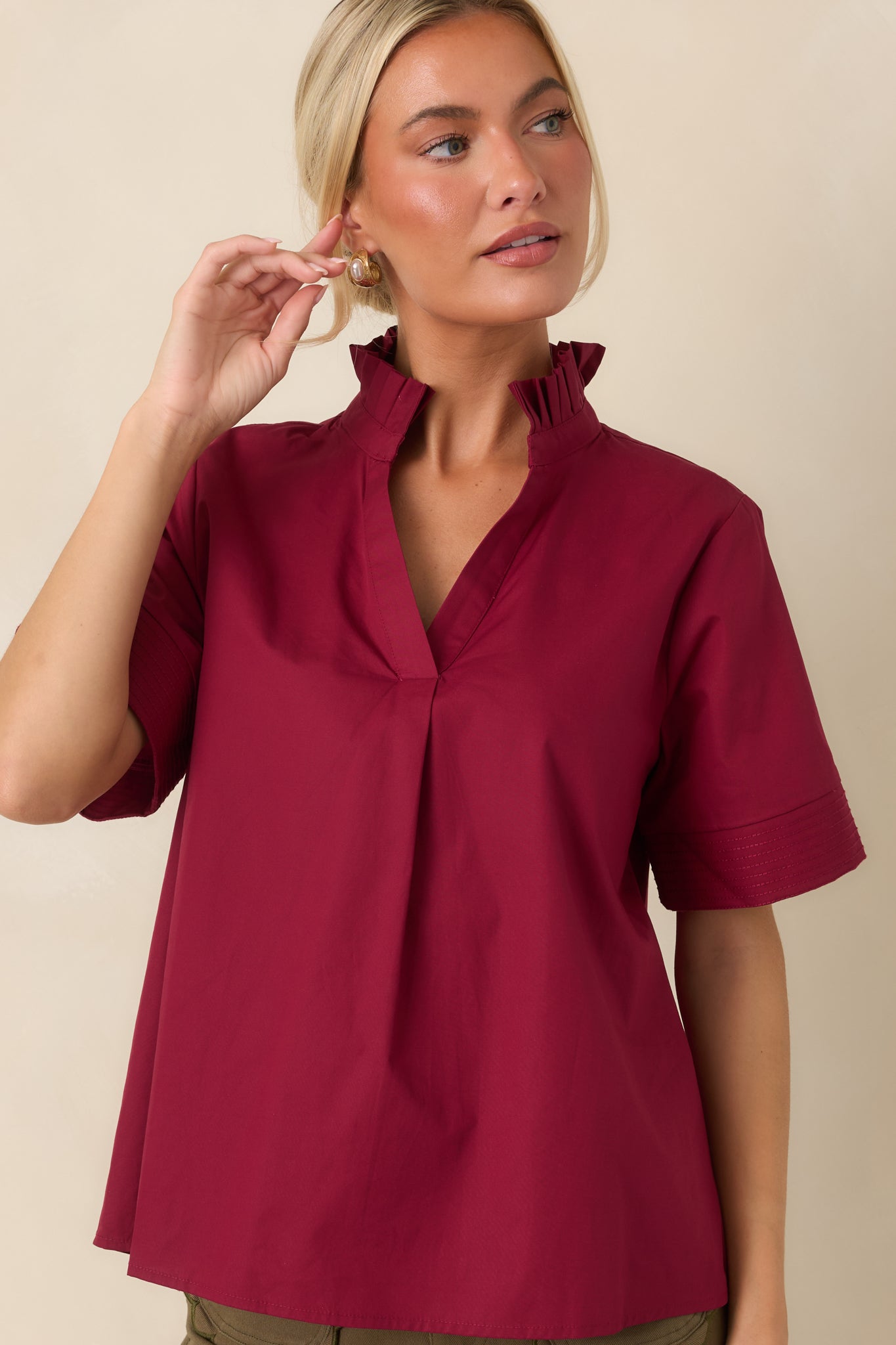 Close view of the softly pleated ruffle collar and split neckline showcasing the top’s feminine detailing.