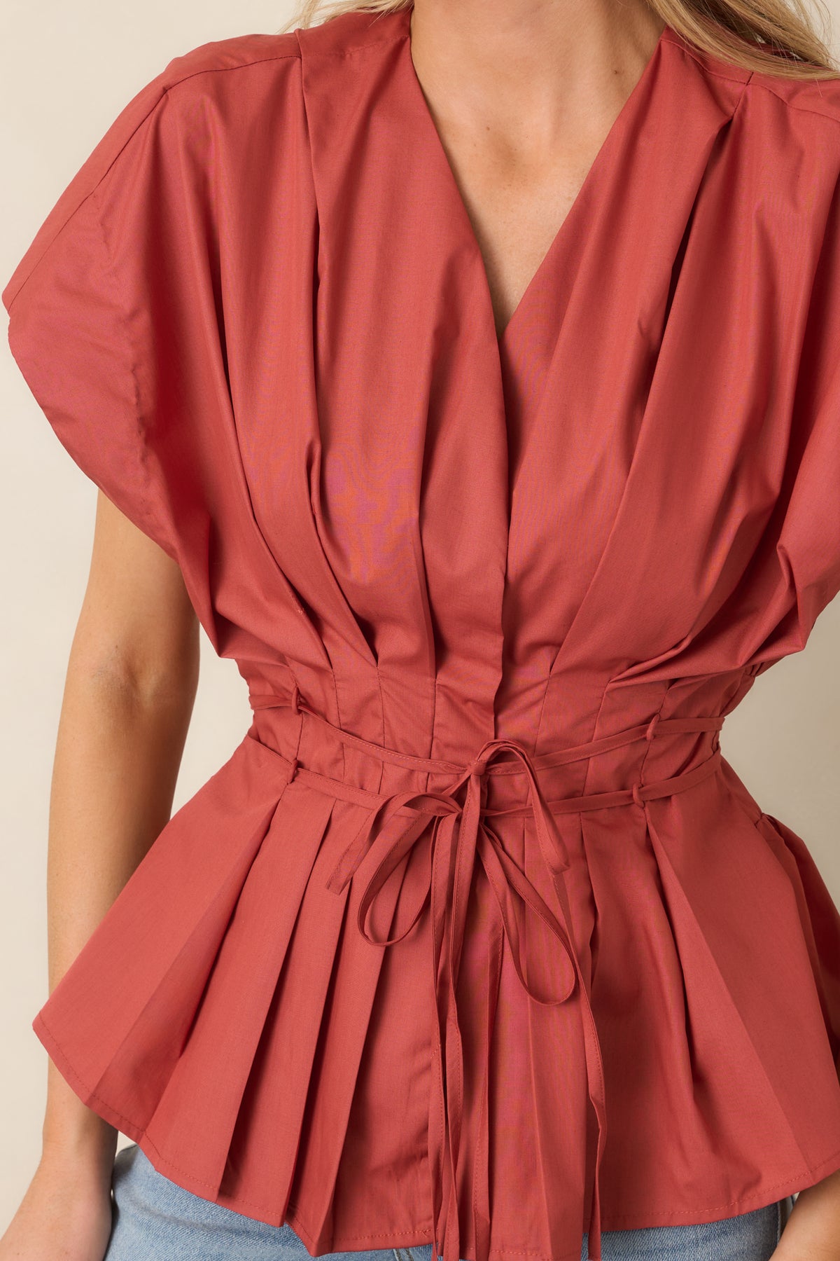 Close-up of the top highlighting crisp pleating around the V-neckline and across the bodice.