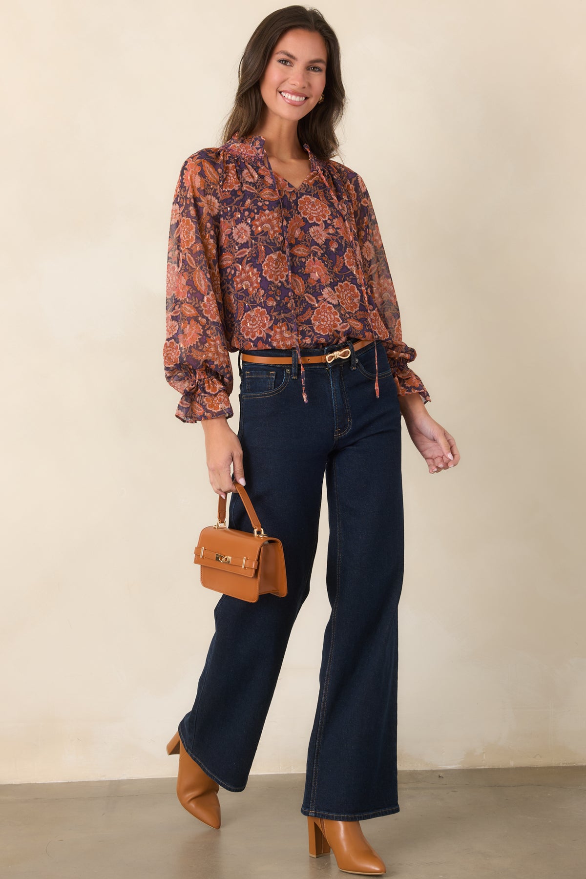 Plum floral top with a layered sheer overlay, lined bodice, and long sleeves finished with ruffled cuffs.