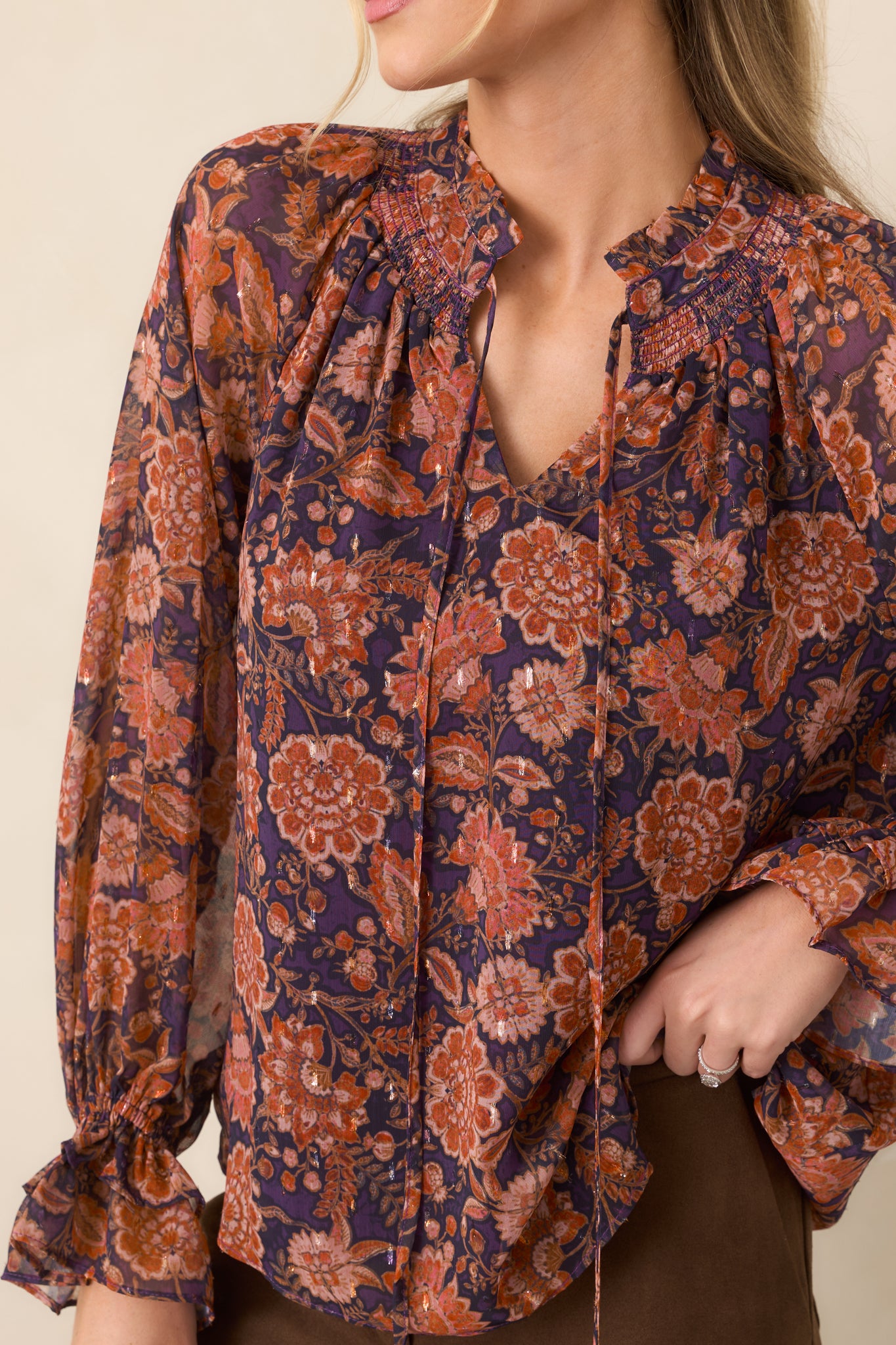 Close-up of the ruffled split neckline, delicate ties, and intricate plum floral overlay.