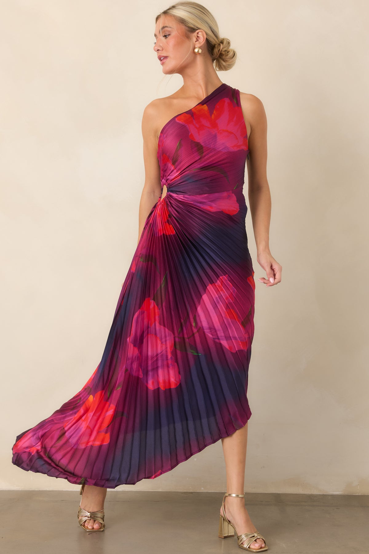 Rich plum and deep indigo provide a dramatic backdrop for fuchsia and scarlet blooms across the pleated dress.
