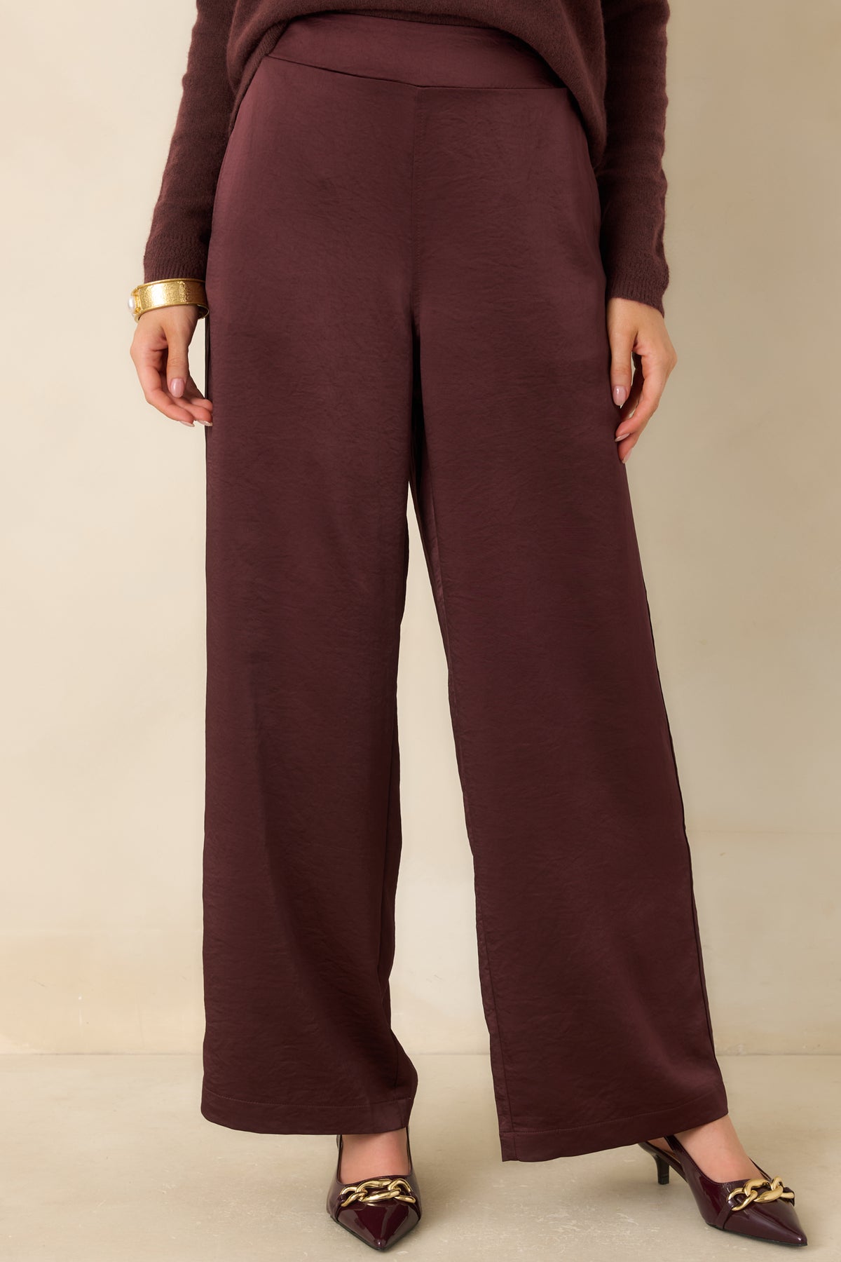 Functional side pocket on the plum-toned satin pants blends into the flowing wide-leg silhouette.