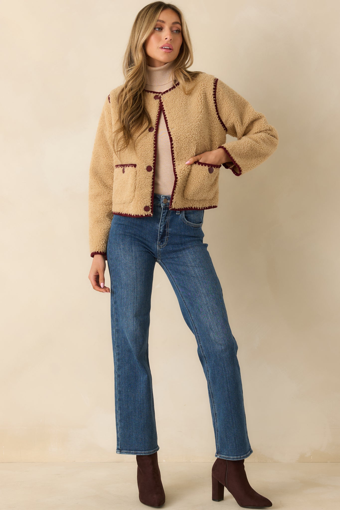 Plush beige jacket featuring crew neckline, patch pockets, and smooth trim accents.