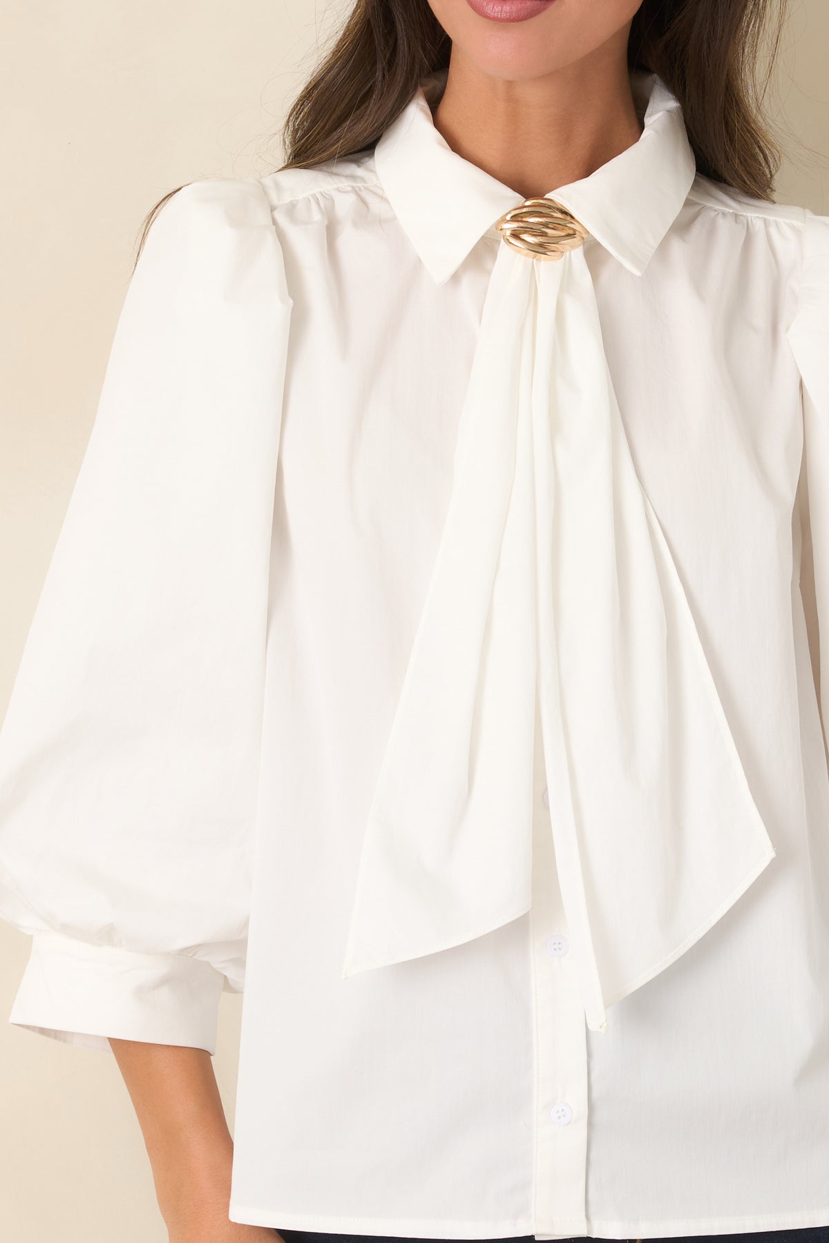 Close-up of the pointed collar, draped neck ties, gold-tone accent, and button-front detailing.
