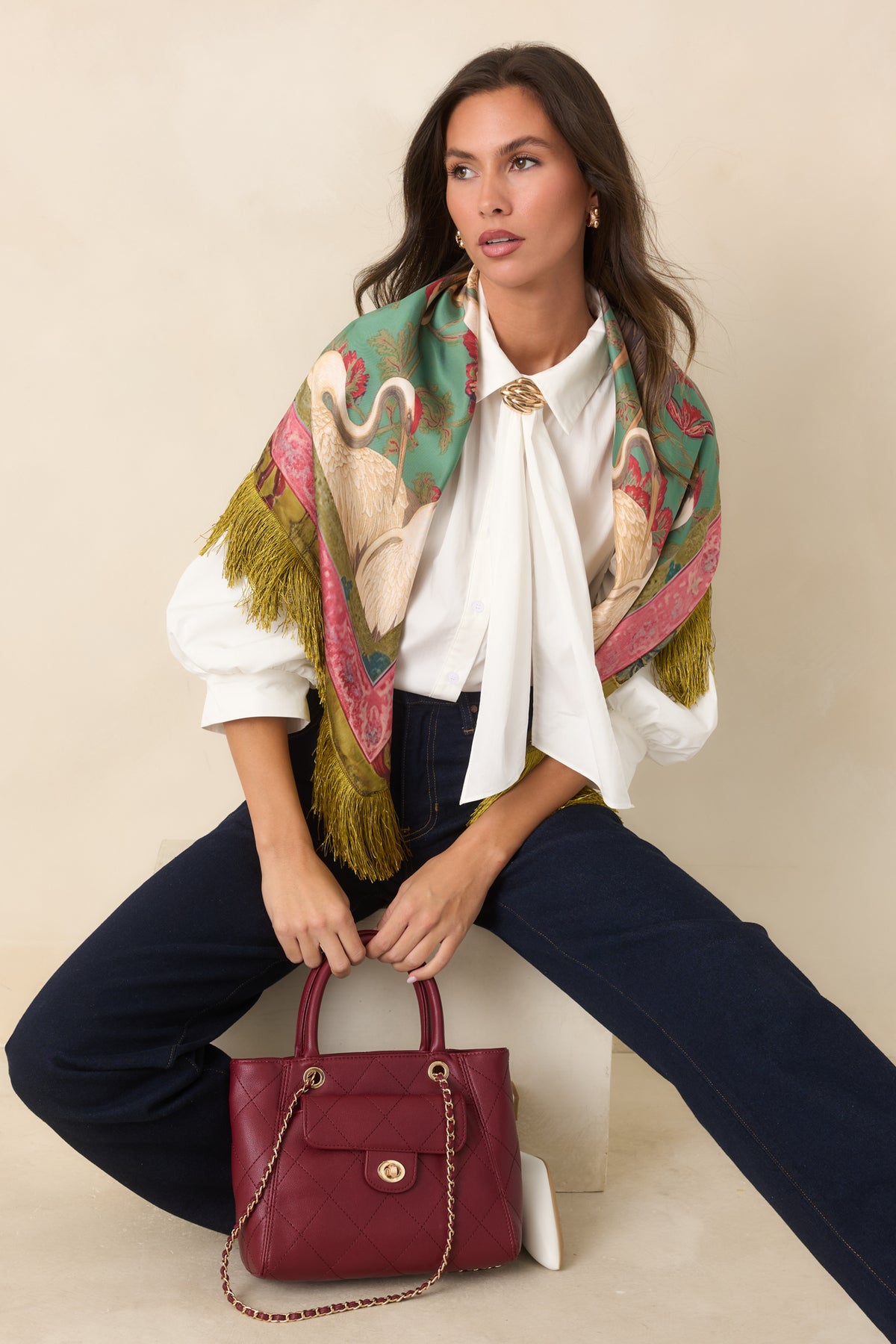Button-front blouse with a pointed collar, draped neck ties, sculptural gold-tone accent, and voluminous three-quarter sleeves.
