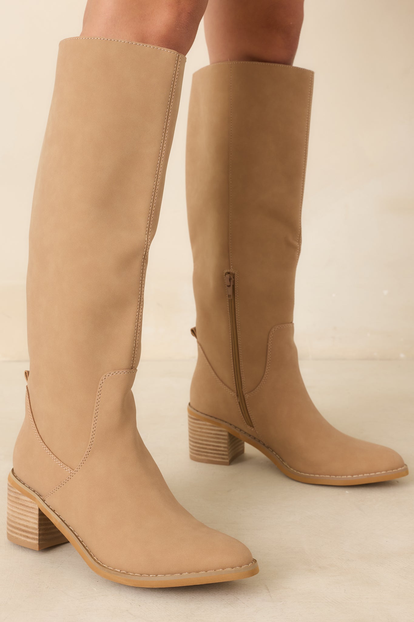 Pointed toe camel boots with a sleek knee-high silhouette and a functional inner side zipper closure.
