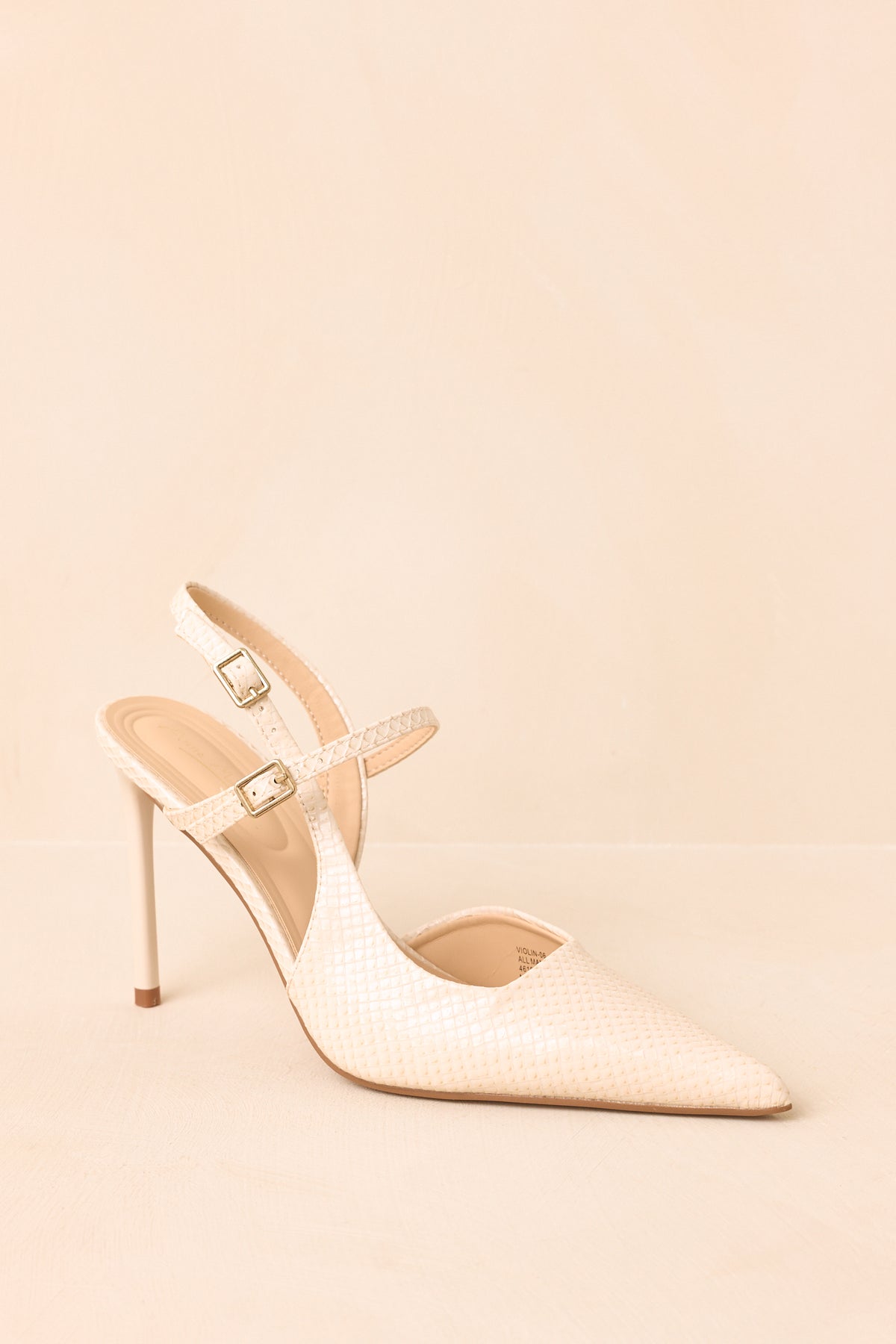 Pointed-toe heels showcase an ivory faux snakeskin finish with a sleek slingback silhouette and delicate double straps.