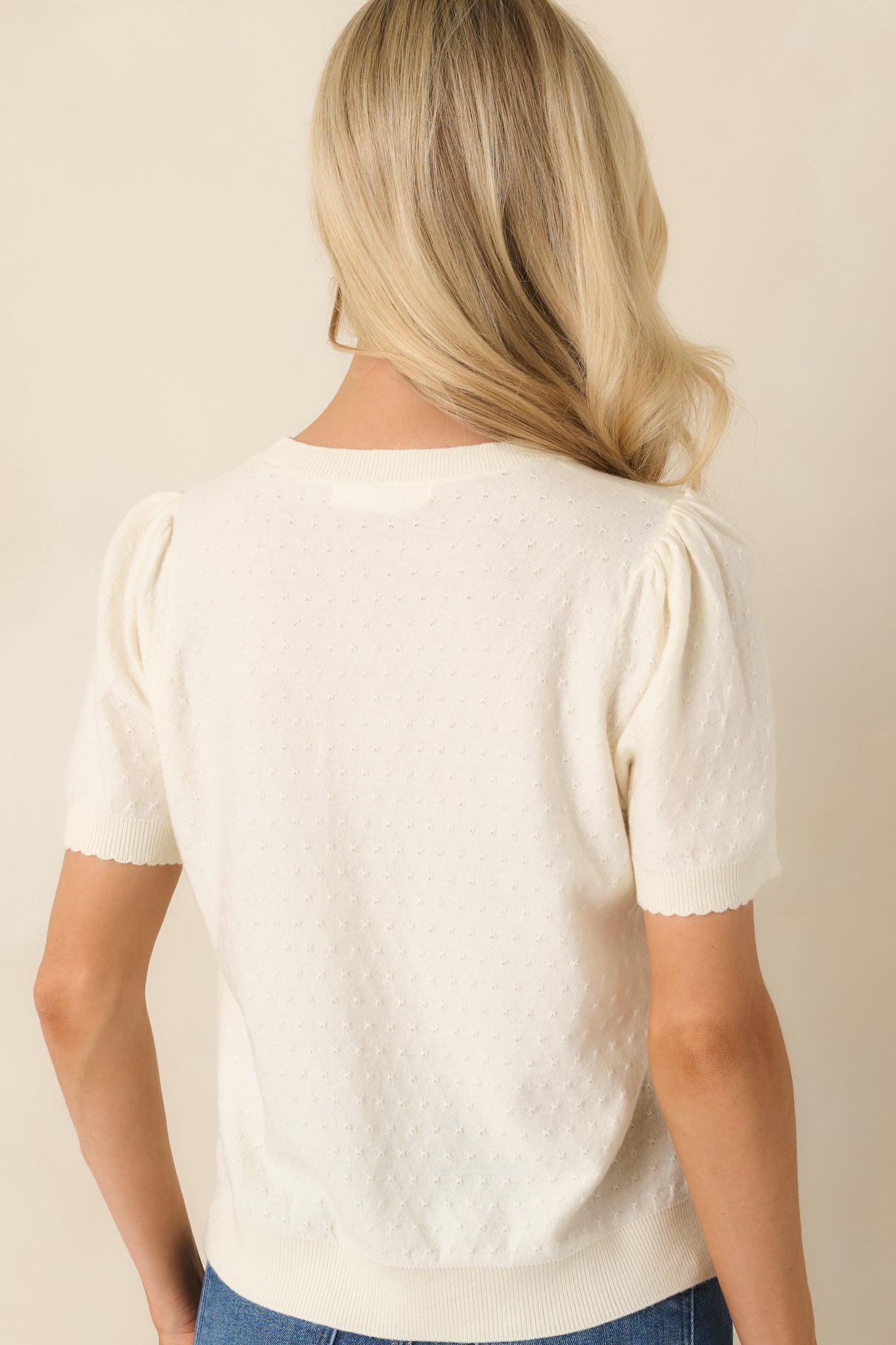 Rear view of the pointelle knit top featuring textured fabric, puff sleeves, and ribbed hem.