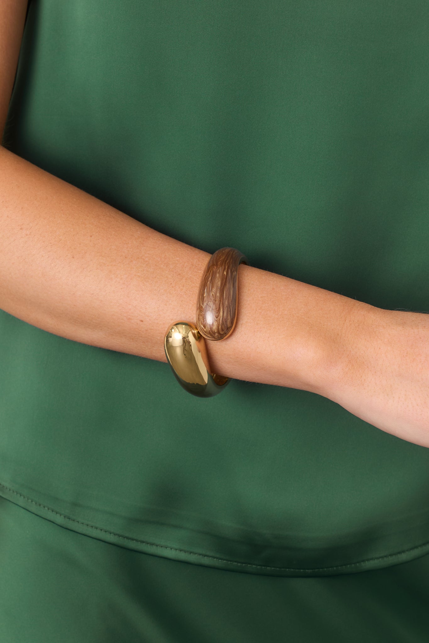 Sculptural cuff bracelet showcasing the contrasting polished gold-tone and brown marbled rounded ends.