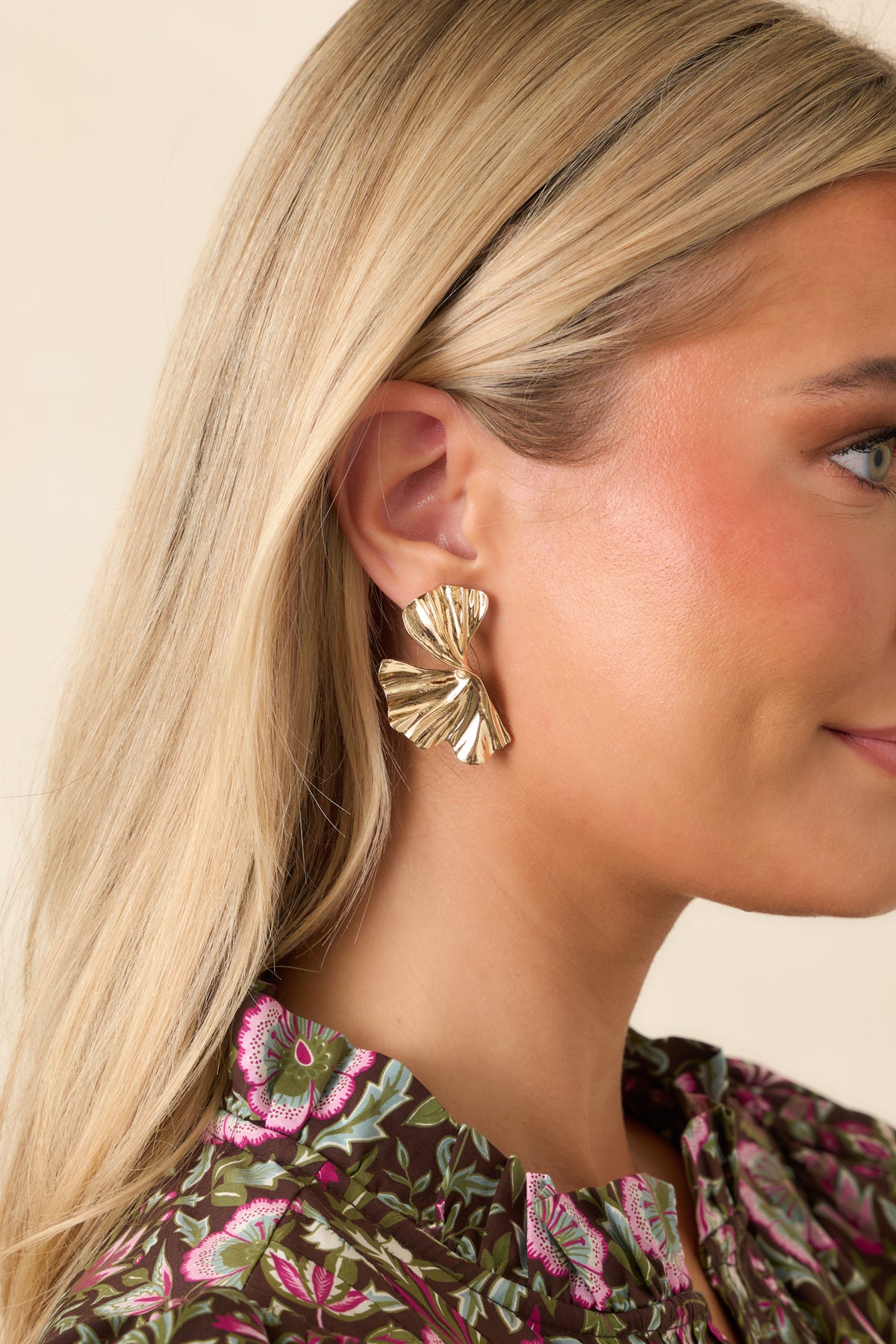 Polished gold-tone earrings showcase a smaller upper fan connected to a wider, wavy lower drop.