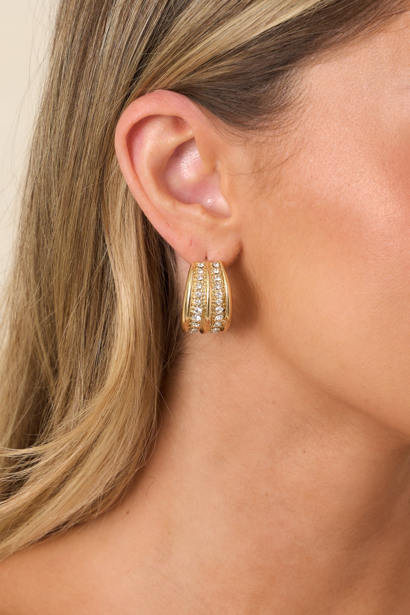 Polished gold-tone hoop earrings accented with multiple rows of sparkling clear crystals for timeless shine.