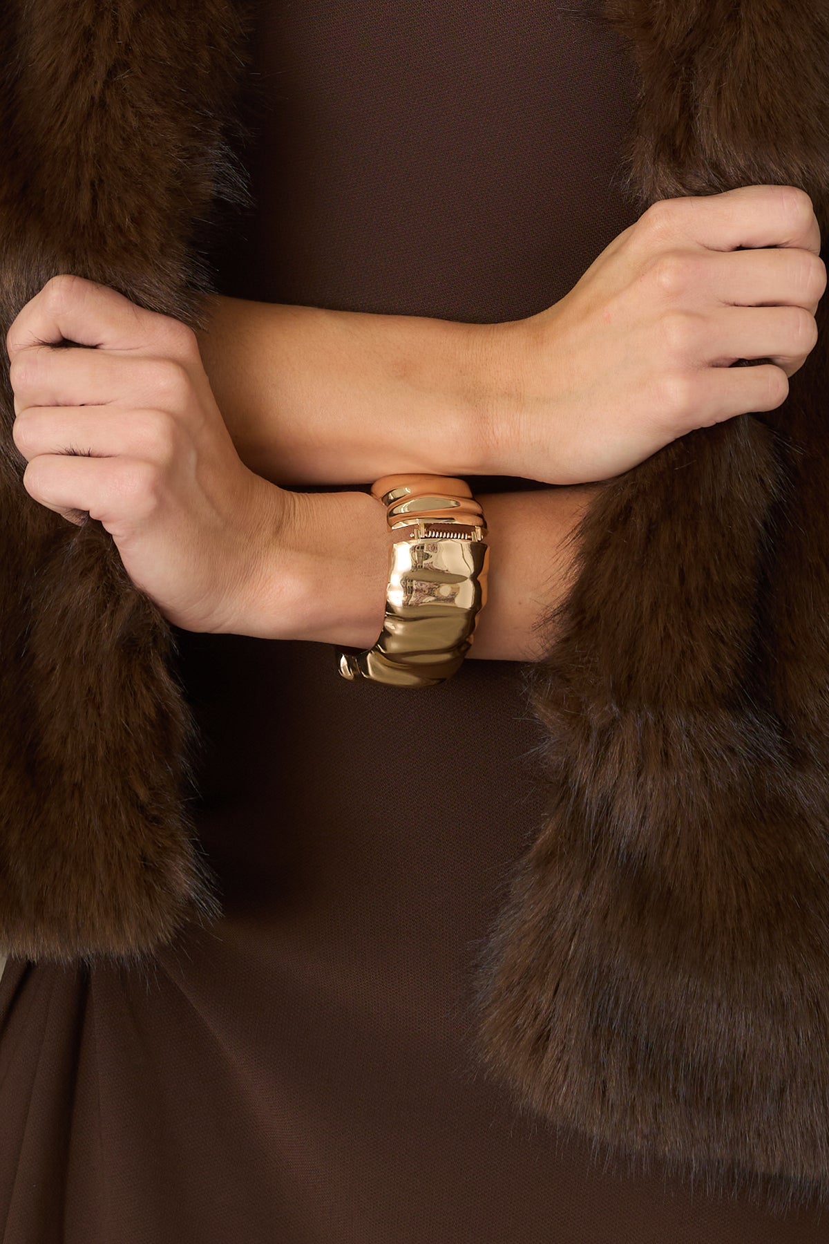 Polished gold-tone cuff bracelet features a sleek statement-making shape with a hinged closure for easy wear.