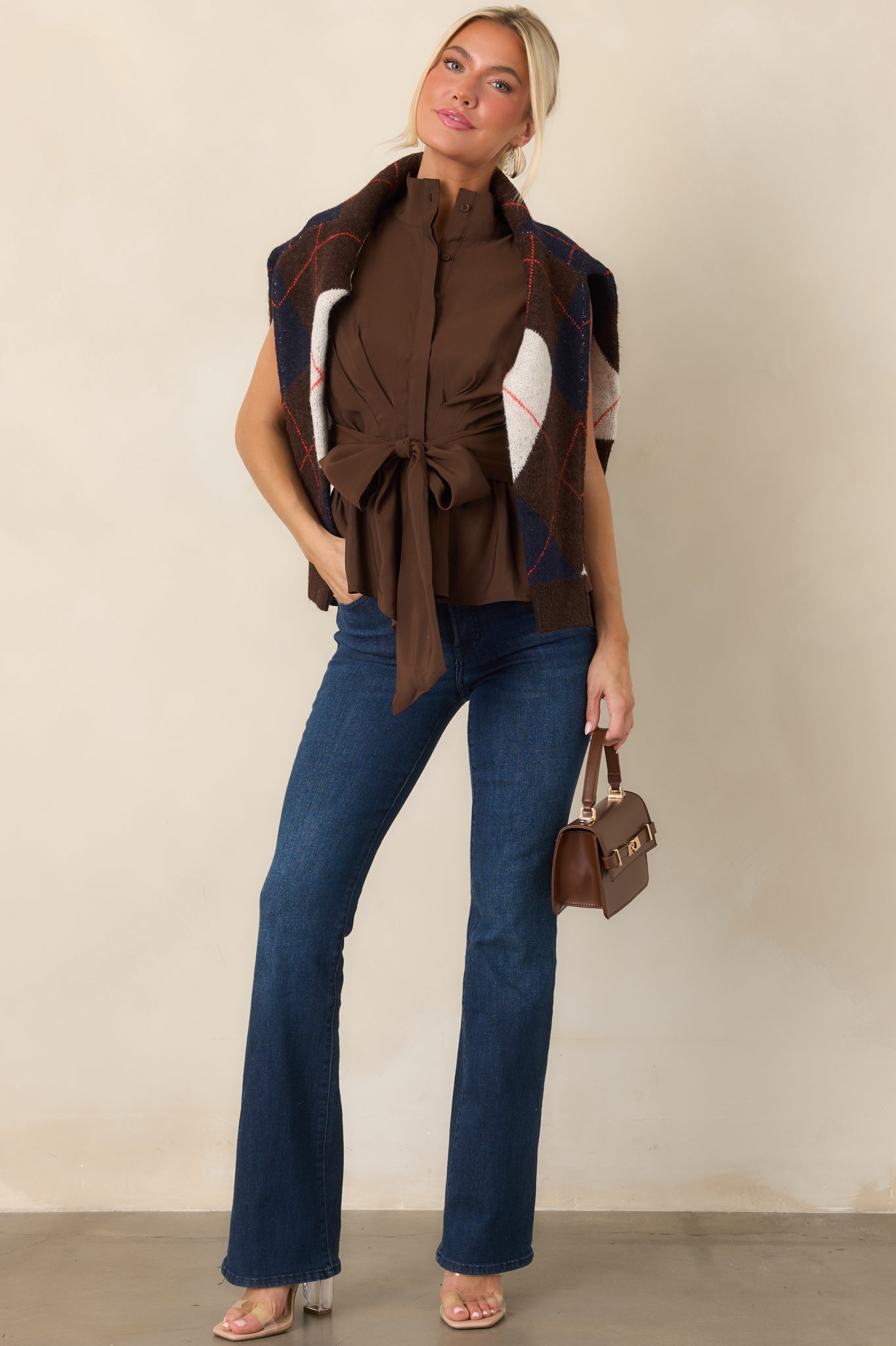 Polished peplum top with a structured stand collar, button placket, defined waist, and oversized tie detail at the front.