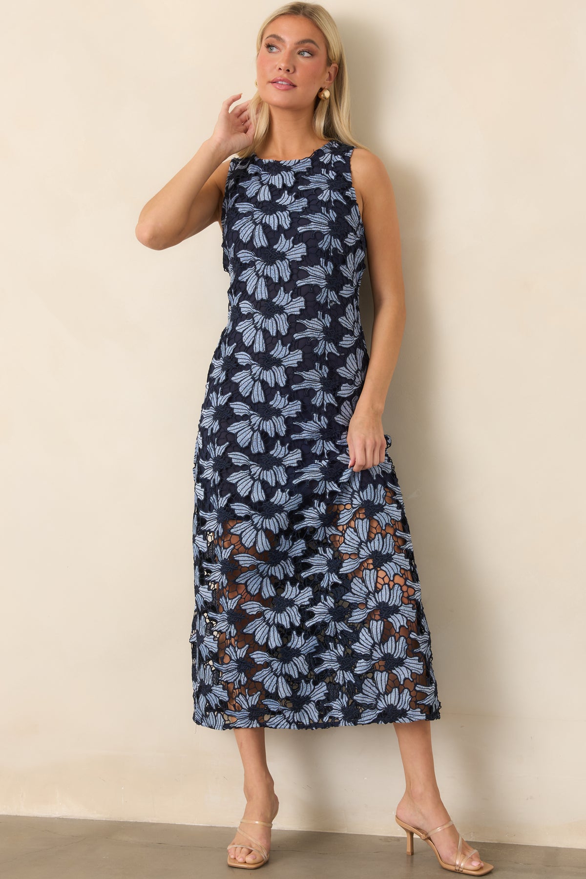 Polished sleeveless dress displaying oversized textured florals, a rounded neckline, and a flowing flared skirt.